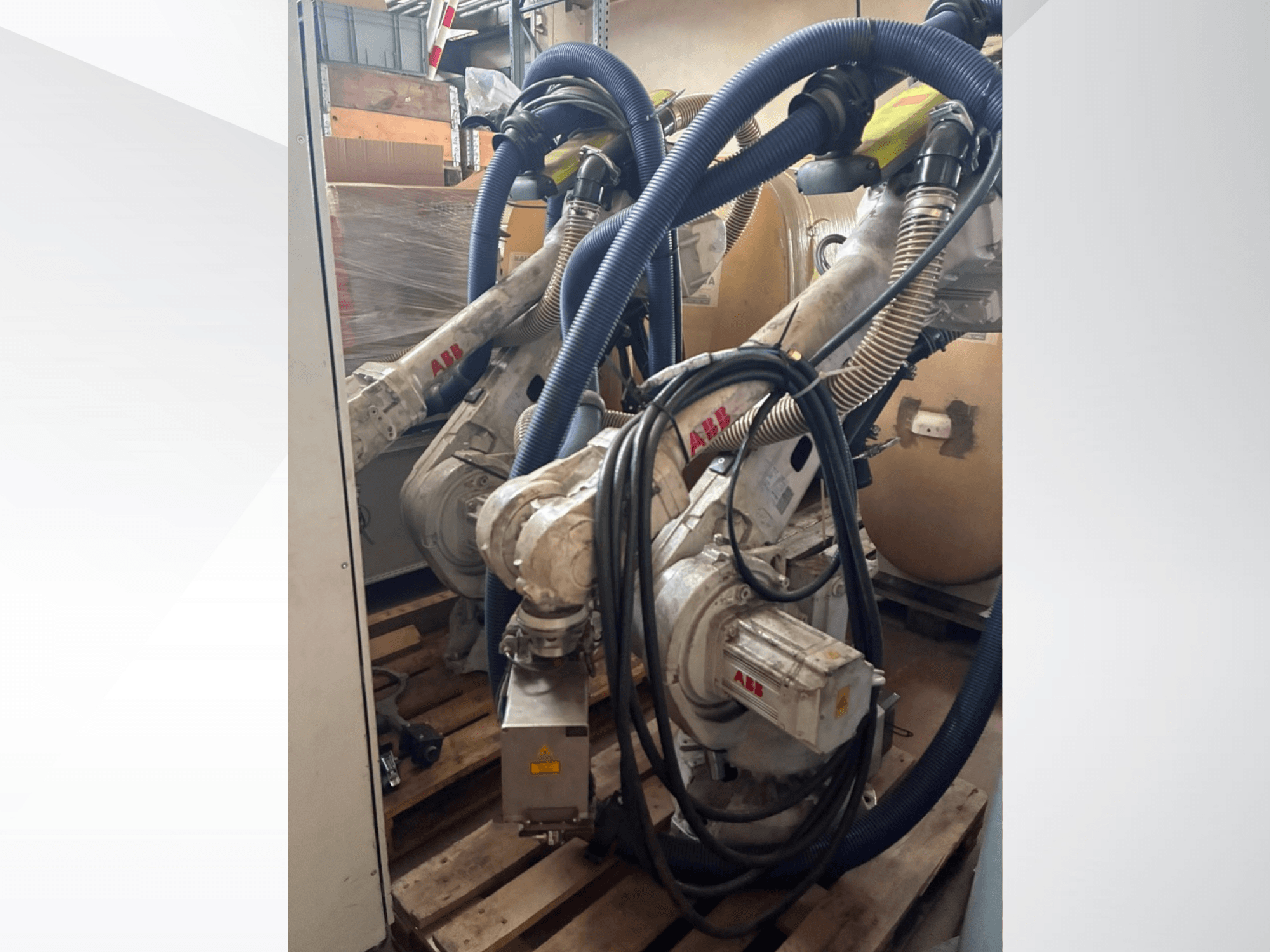 Ramię robota ABB IRB 4600-40/2.55, widok z boku przedstawiający dwa ramiona i podłączone węże, zamontowane na paletach w magazynie.
