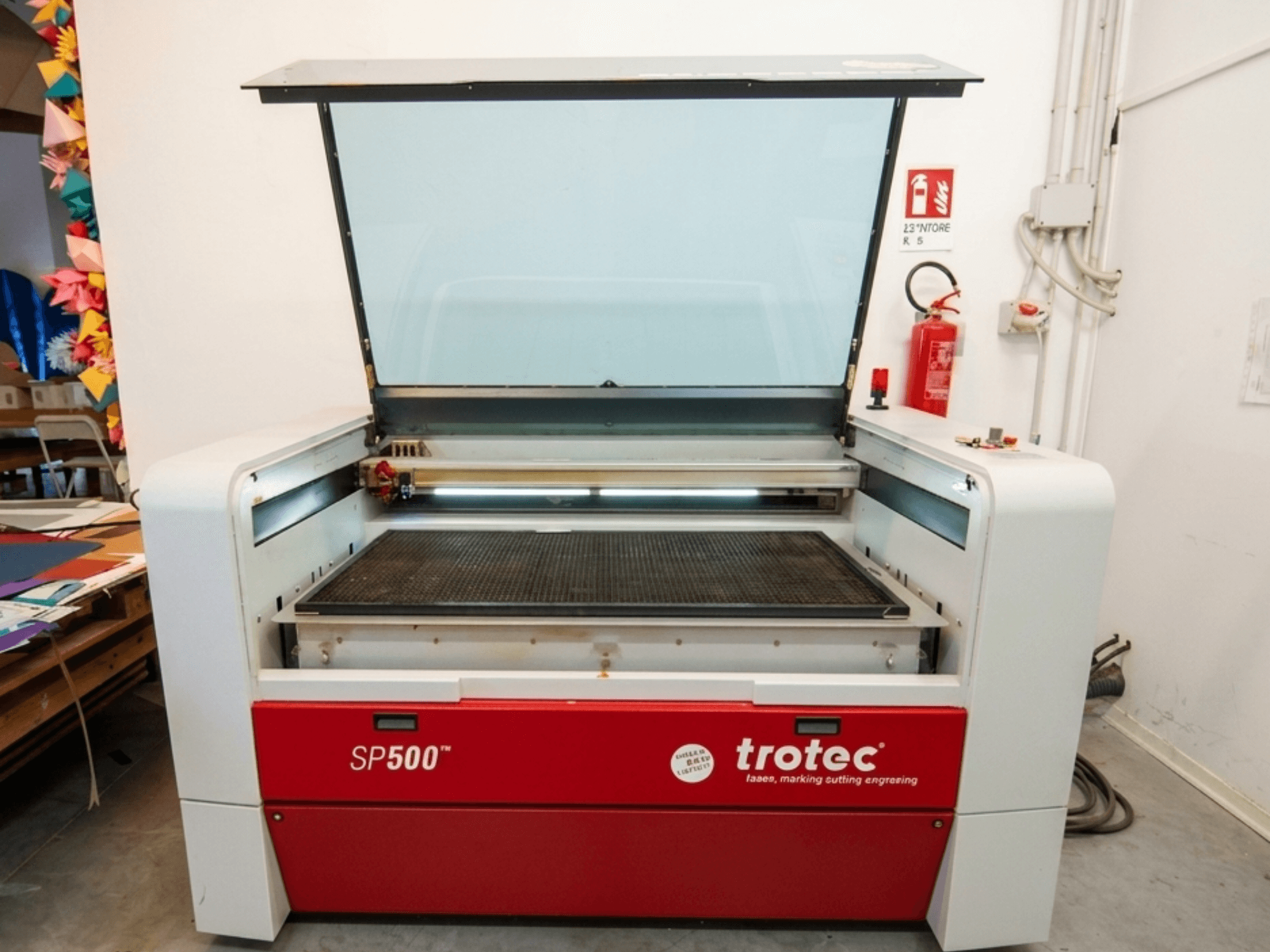 Maszyna do grawerowania laserowego Trotec SP500 C200 w widoku z przodu, z otwartą pokrywą pokazującą obszar roboczy i elementy sterujące.