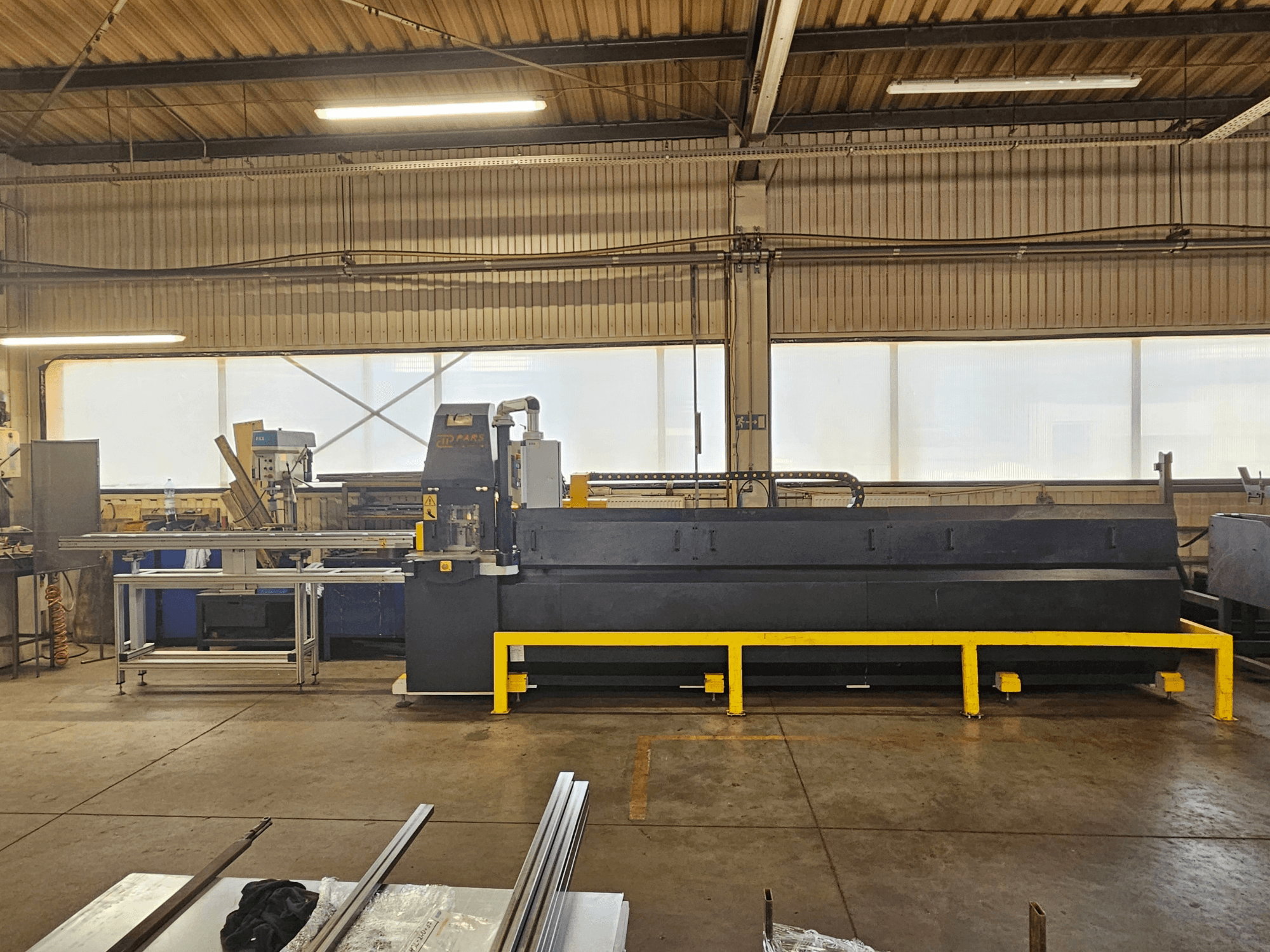 Wykrawarka CNC PARS HMP SIRIUS PLUS-3000/3-L1, widok z przodu w środowisku przemysłowym, z metalową powierzchnią i narzędziami.