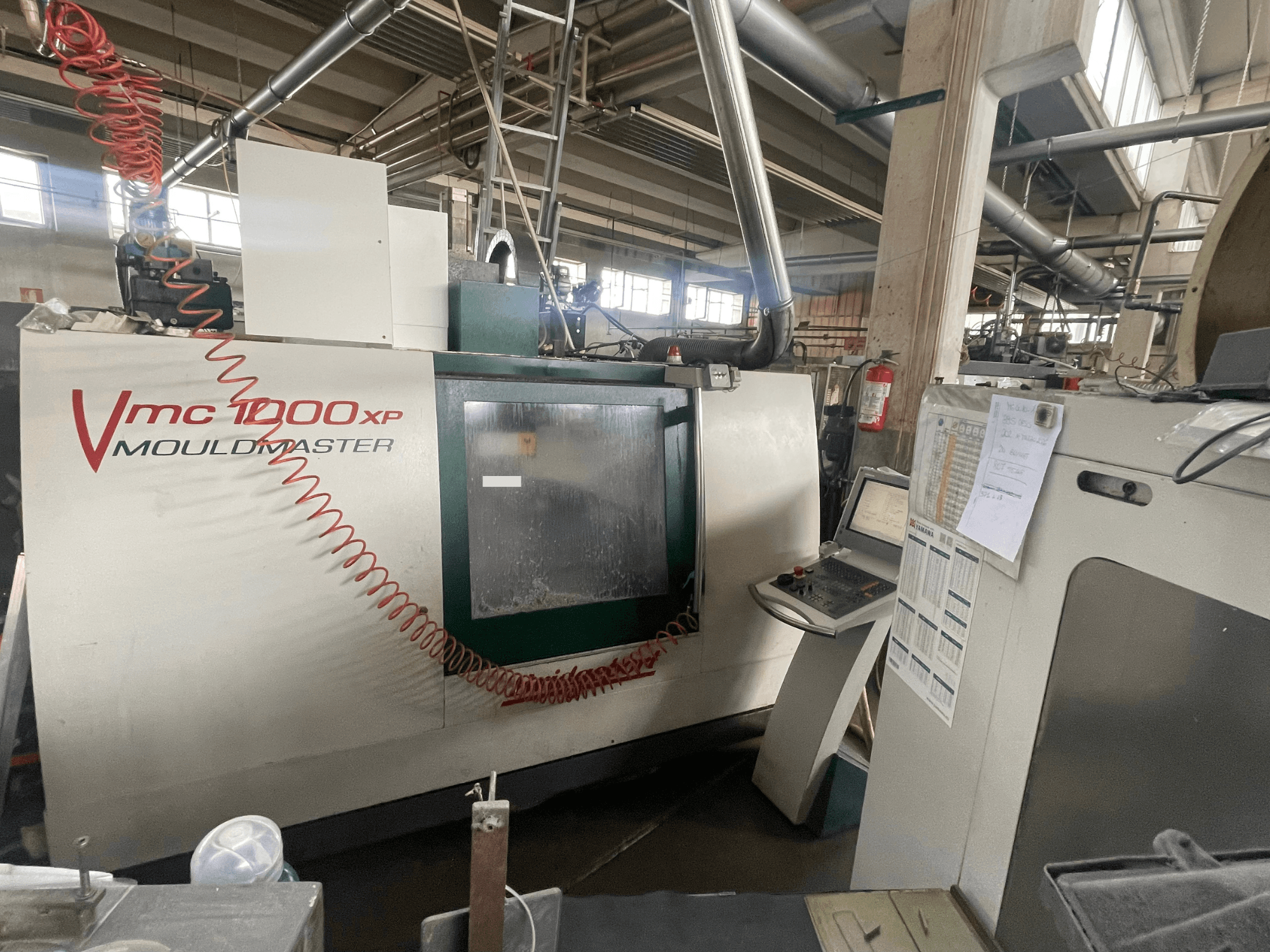 Pionowe centrum obróbcze Bridgeport VMC 1000, widok z przodu, przedstawiający panel sterowania i szczegóły maszyny w otoczeniu przemysłowym.