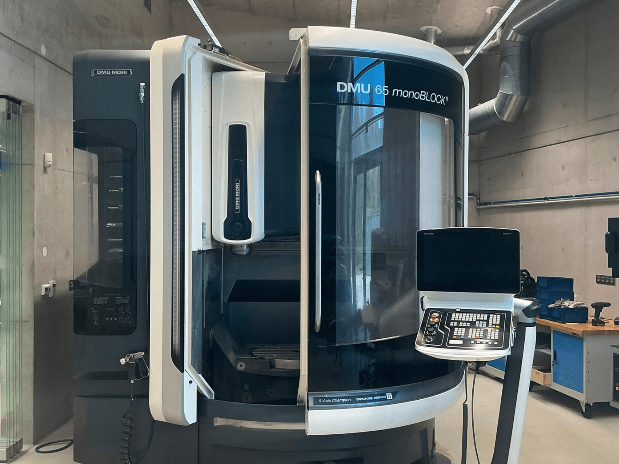 Pionowe centrum obróbcze DMG MORI DMU 65 monoBLOCK, widok z przodu, przedstawiający panel sterowania oraz szczegóły maszyny w warunkach warsztatowych.