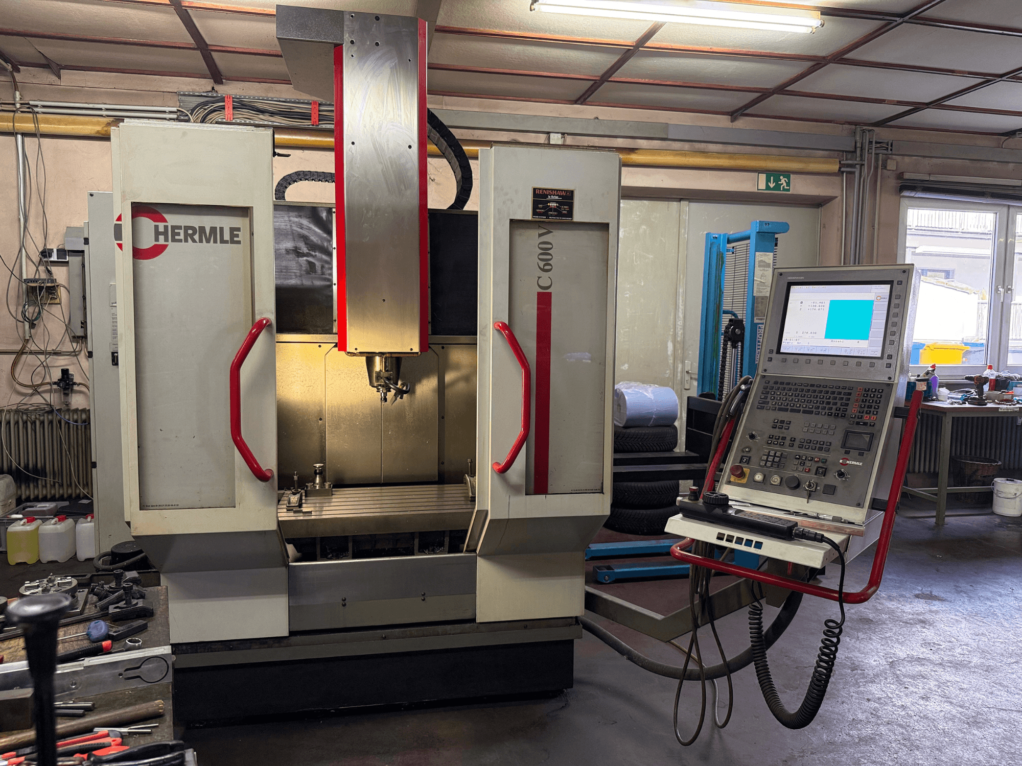 Frezarka CNC Hermle C 600 w widoku z przodu, z panelem sterowania z licznymi przyciskami i przestronnym obszarem roboczym.
