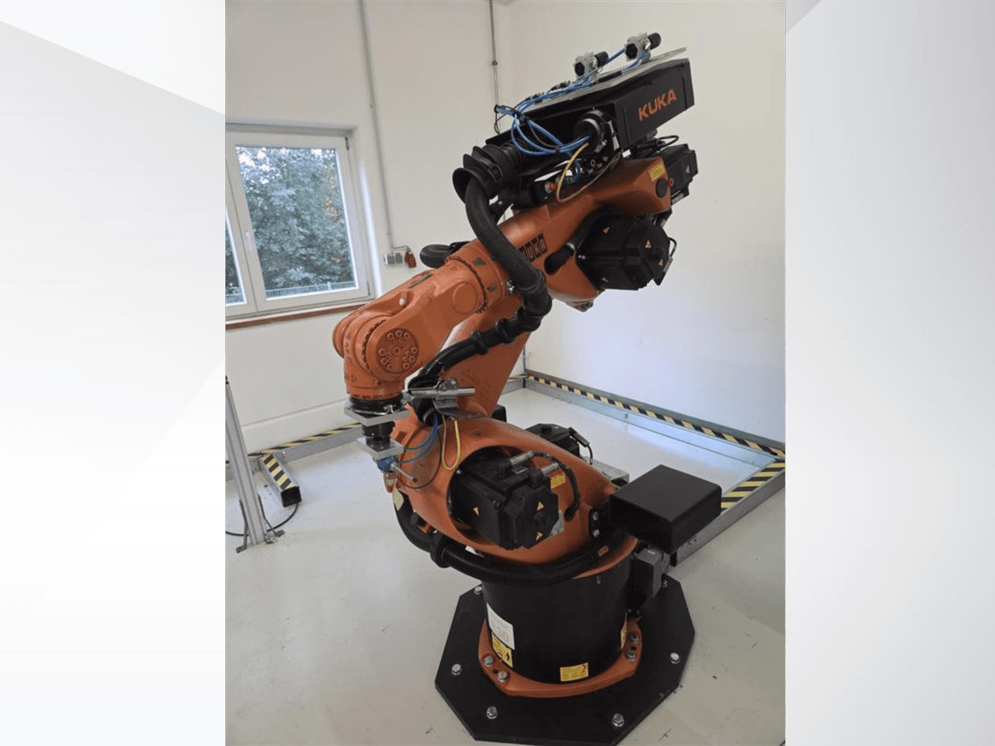 Ramię robota KUKA KR60 HA widziane z boku, przedstawiające przeguby mechaniczne i okablowanie na podstawie przemysłowej.