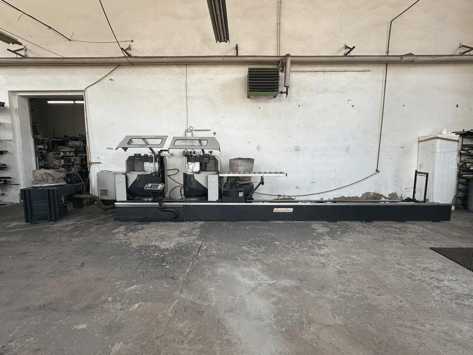 Pilarka tarczowa do metalu Elumatec DG 244 w warsztacie, widok z boku przedstawiający dwie piły i elementy sterujące na solidnej podstawie.