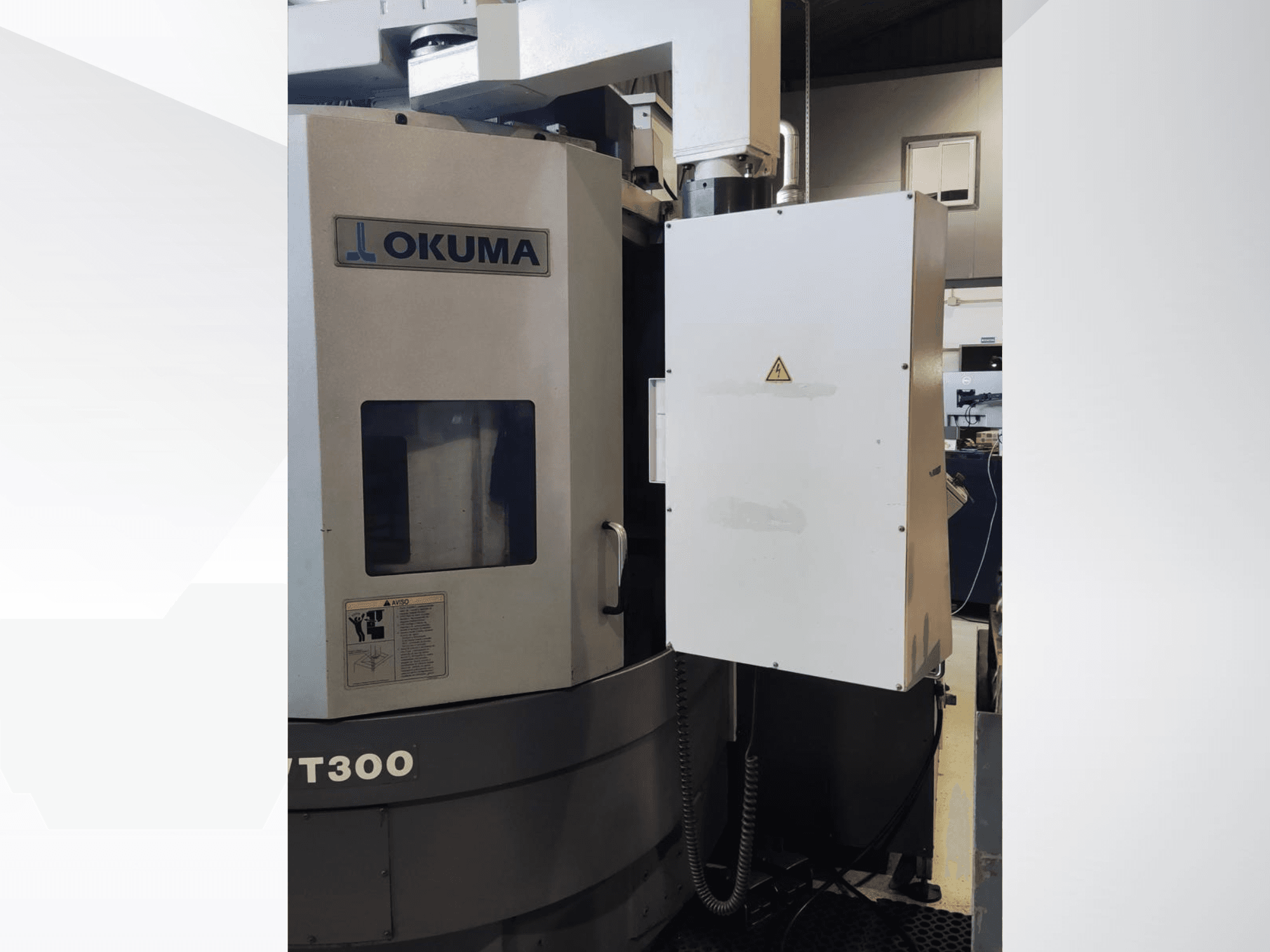 Tokarka pionowa Okuma LVT300, widok z przodu, z panelem sterowania i oznaczonymi funkcjami bezpieczeństwa.