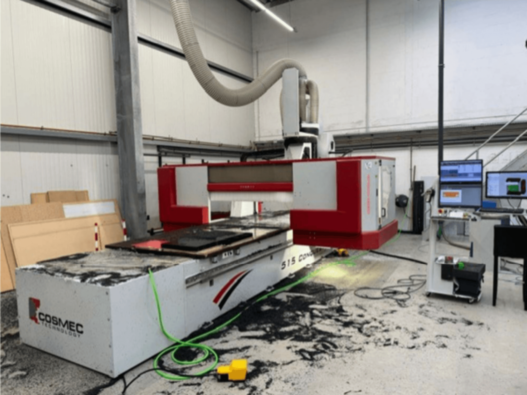 Maszyna CNC Cosmec 515 w warsztacie z terminalem komputerowym, widok z przodu i kurz rozsypany na powierzchni.