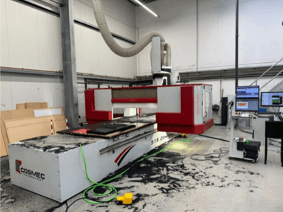 Maszyna CNC Cosmec 515 w warsztacie z terminalem komputerowym, widok z przodu i kurz rozsypany na powierzchni.