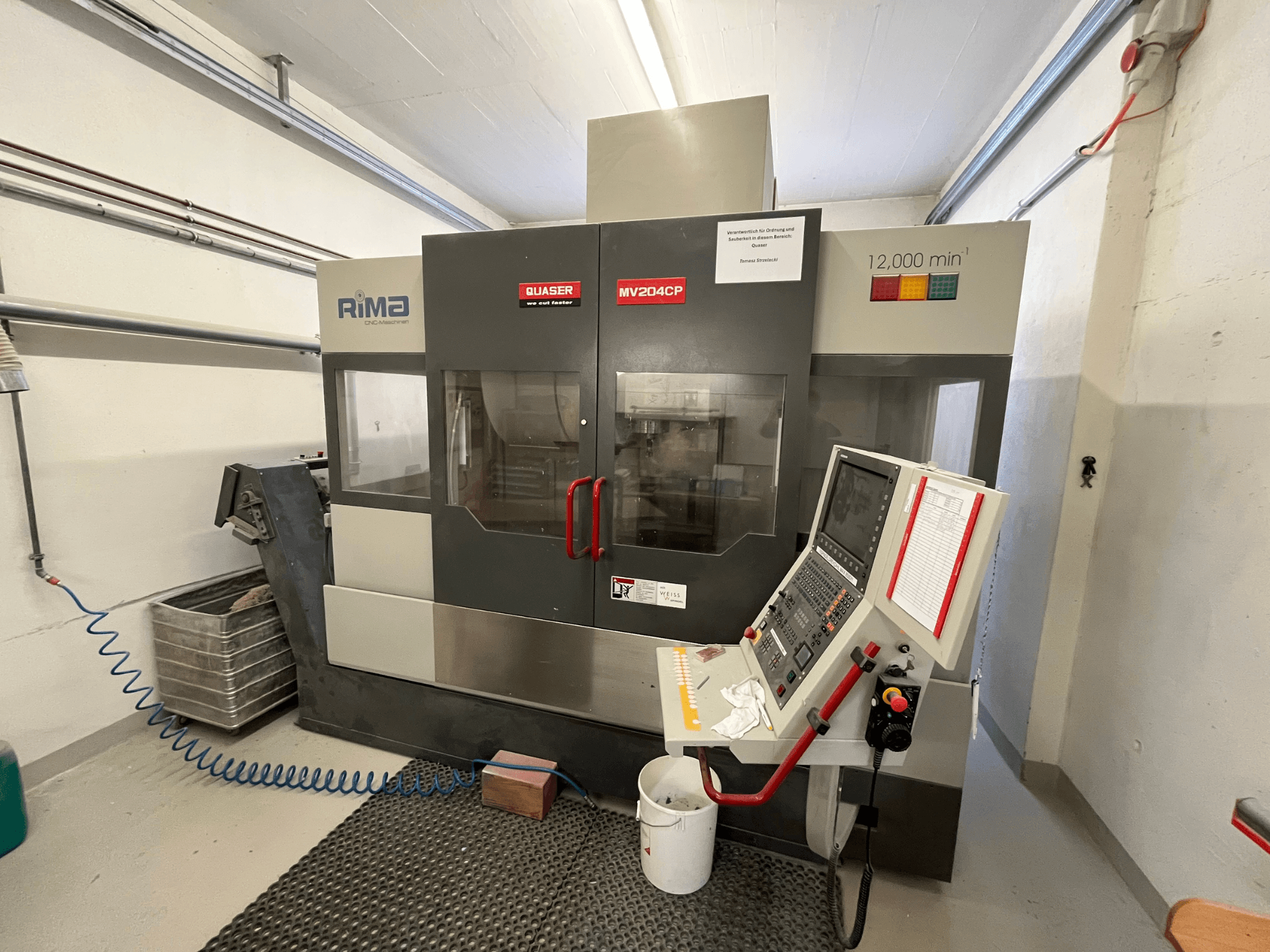 Pionowe centrum obróbcze Quaser MV-204 CP w widoku z przodu, z panelem sterowania i szczegółami operacyjnymi.