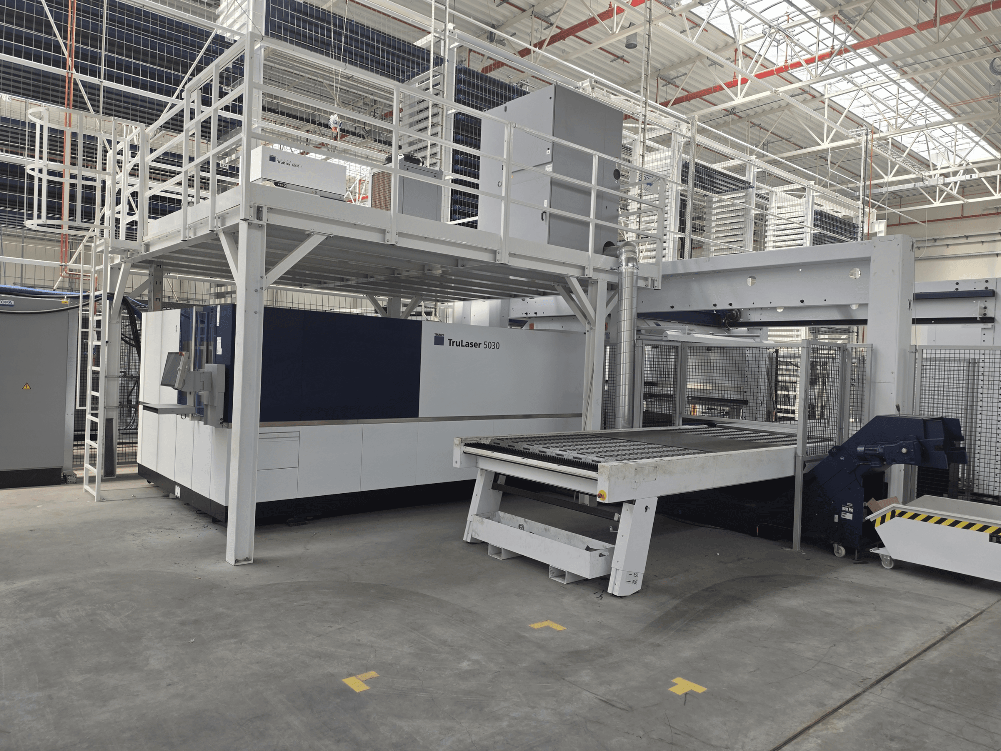 Maszyna TRUMPF TruLaser 5030 fiber L76 FMC w warsztacie – widok z przodu przedstawiający obszar cięcia oraz mechanizm załadowczo-rozładowczy.