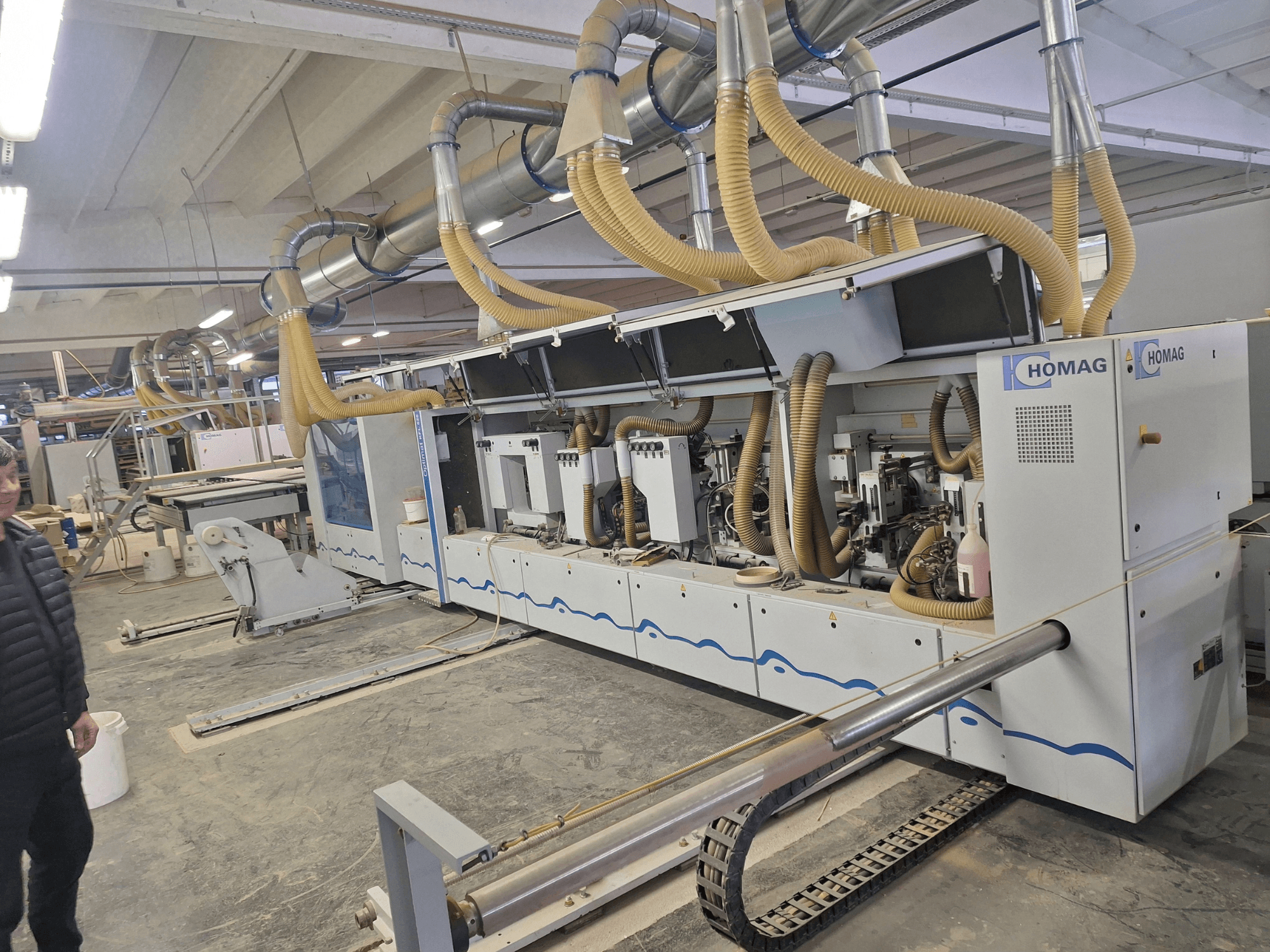 Maszyna do obróbki drewna HOMAG w warunkach fabrycznych, widok z przodu pokazujący wiele wrzecion i system odsysania pyłu.