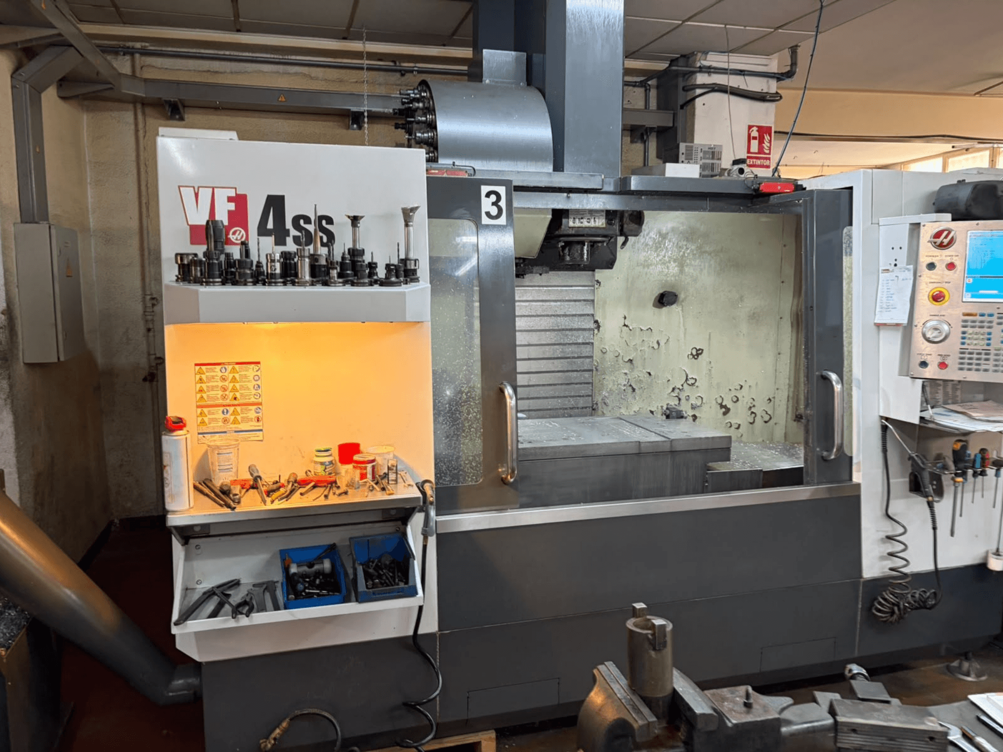Pionowe centrum obróbcze HAAS VP 4SS, widok z przodu, z magazynem narzędzi, panelem sterowania oraz widocznym obszarem roboczym wraz ze szczegółami obróbki.