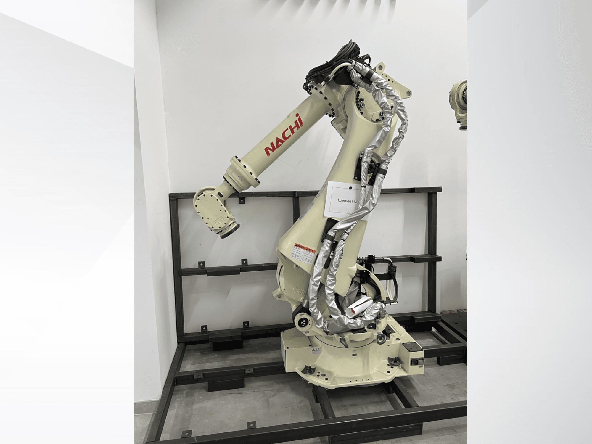 Ramię robota NACHI SRA166-01 w widoku z boku, wyposażone w elastyczne przeguby, podłączone kable i zamontowane na ramie ochronnej.