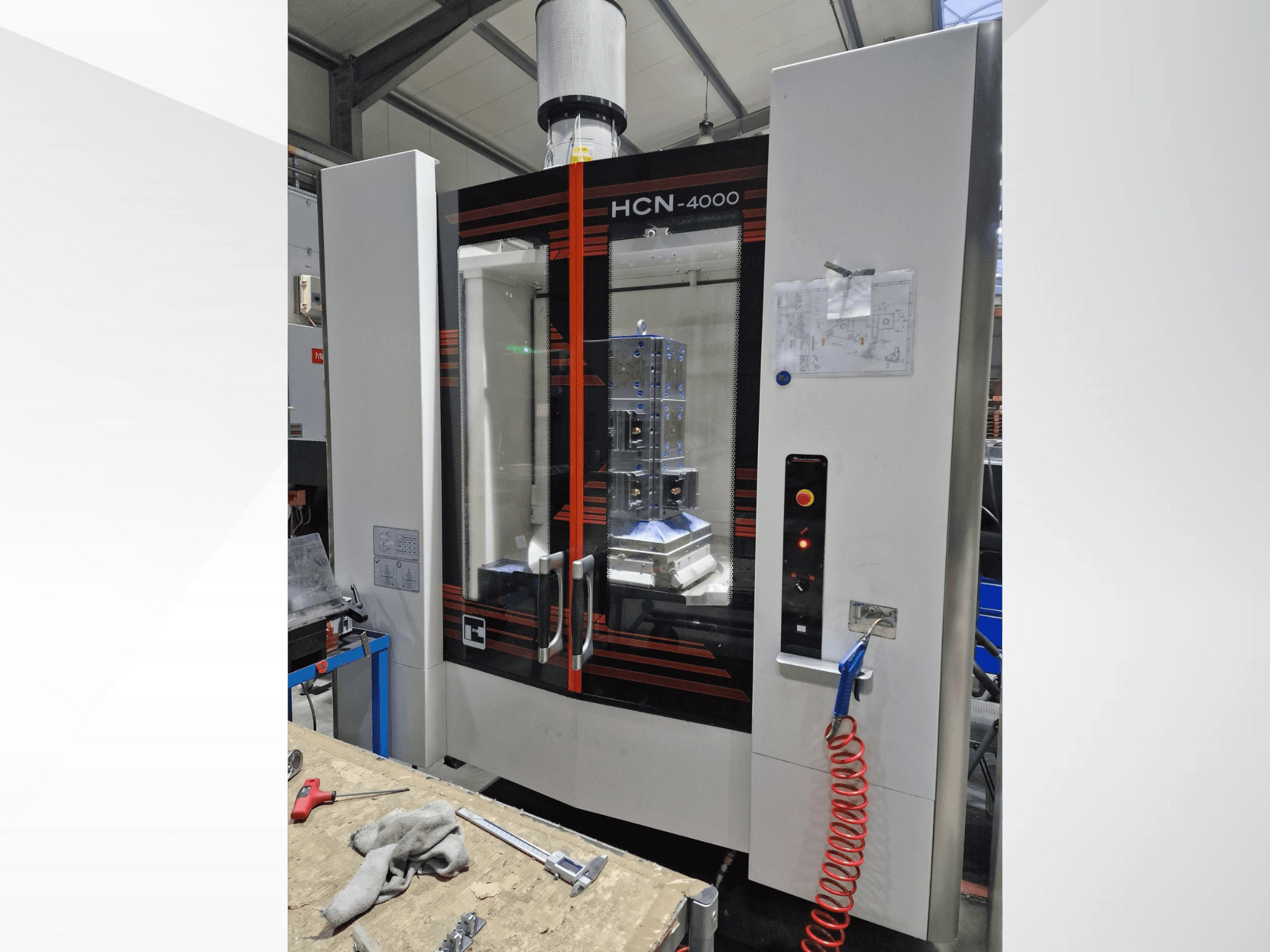 Maszyna CNC HCN-4000 w widoku z przodu, ze szklanym panelem, panelem sterowania z przyciskami i dołączonym schematem.