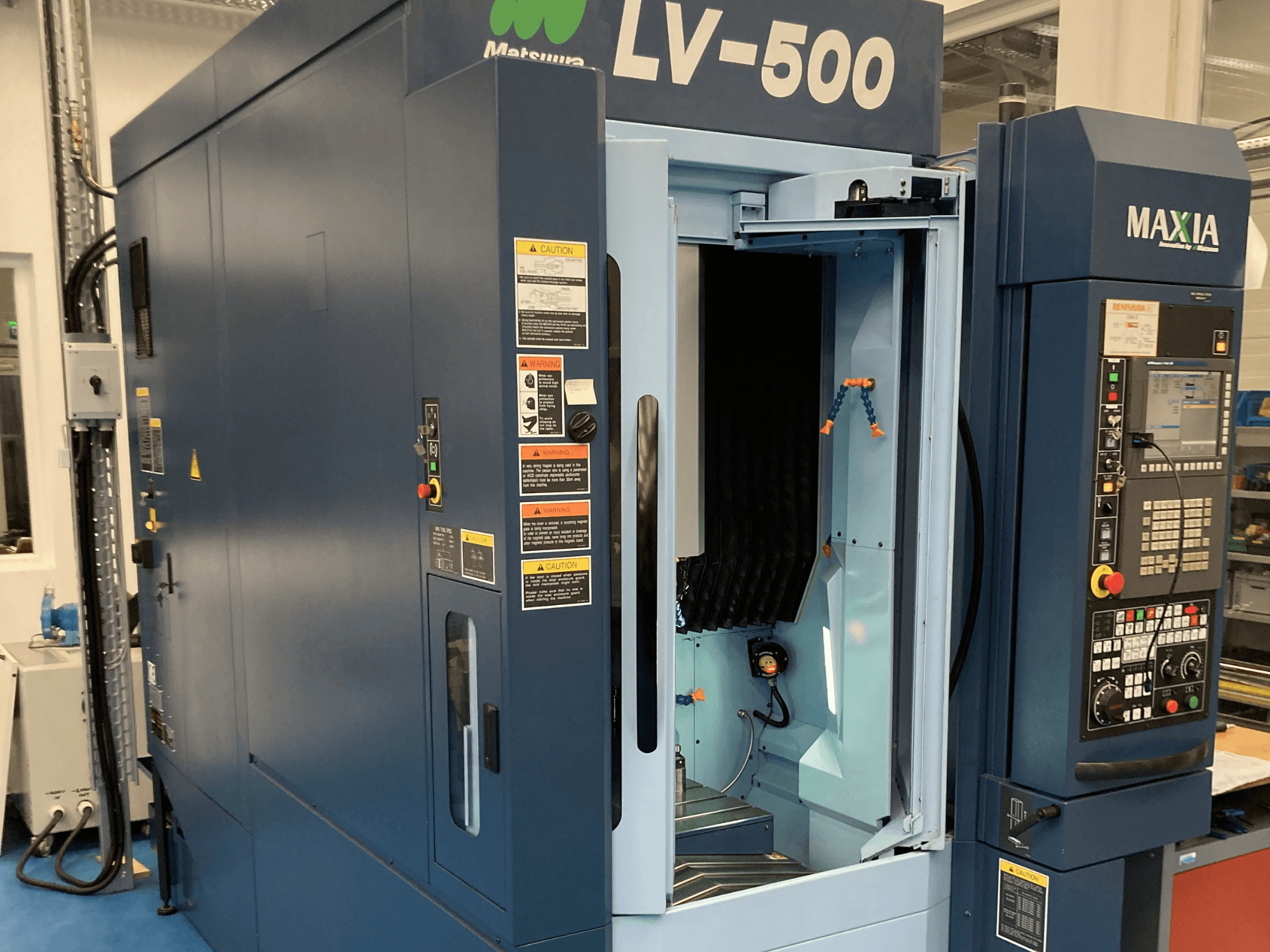 Pionowe centrum obróbcze Matsuura LV-500 pokazane z przodu, z otwartymi drzwiami i panelem sterowania z przyciskami.