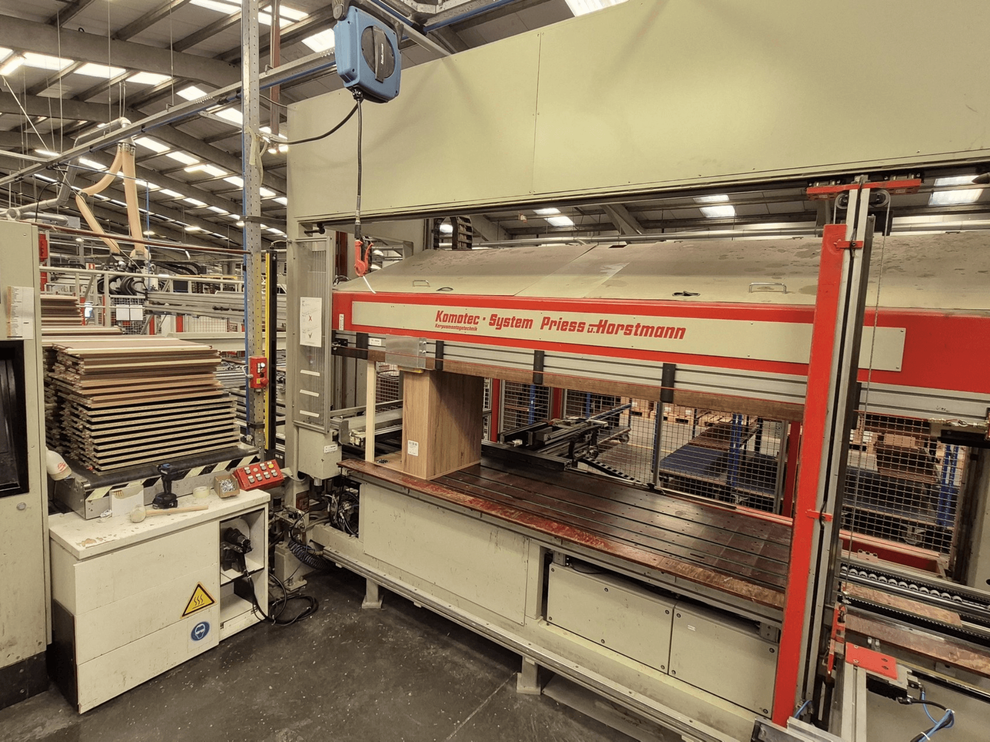 Prasa do forniru KP-5-CNC firmy PREISS U HORTSTMANN, widok z przodu, pokazujący ułożone arkusze forniru i panel sterowania.