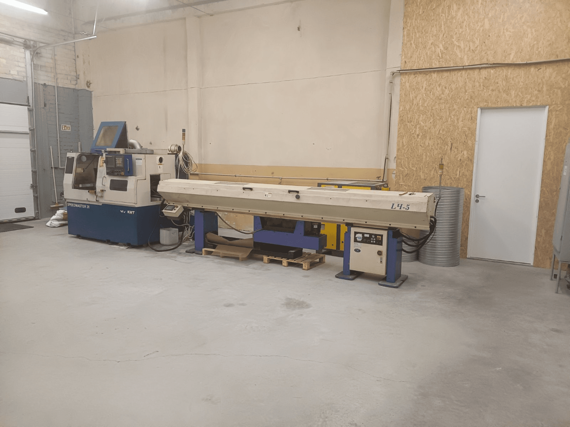 Warsztat przemysłowy z maszyną KMT Speedmaster 34 i L4.5, widziany z przodu, z widocznymi elementami sterującymi i maszynami.