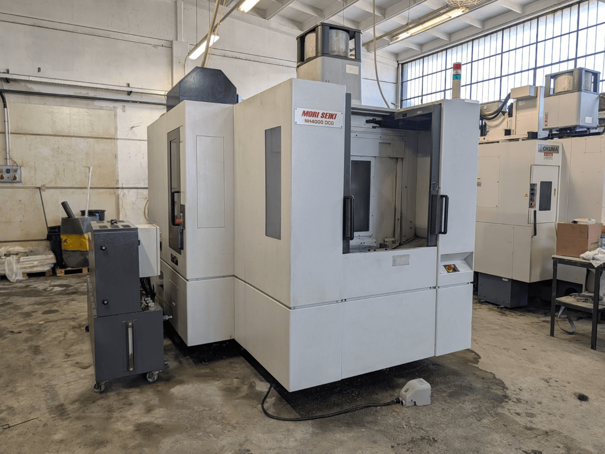 Poziome centrum obróbcze MORI SEIKI NH 4000 DCG, widok z przodu, panel sterowania i obszar roboczy, wykończenie w kolorze szarym i białym.