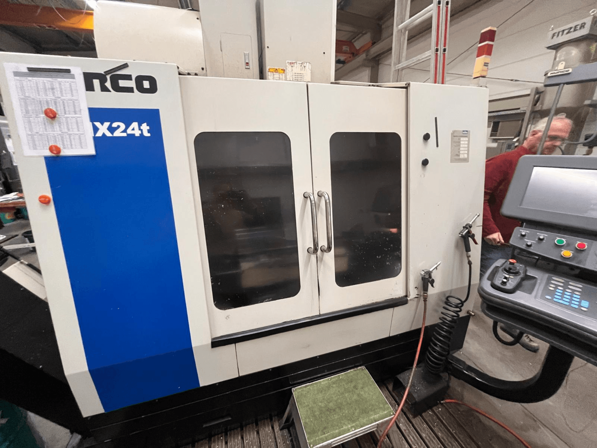 Pionowe centrum obróbcze firmy Hurco, model VX24t, pokazane od przodu z panelem sterowania i przezroczystymi drzwiami.