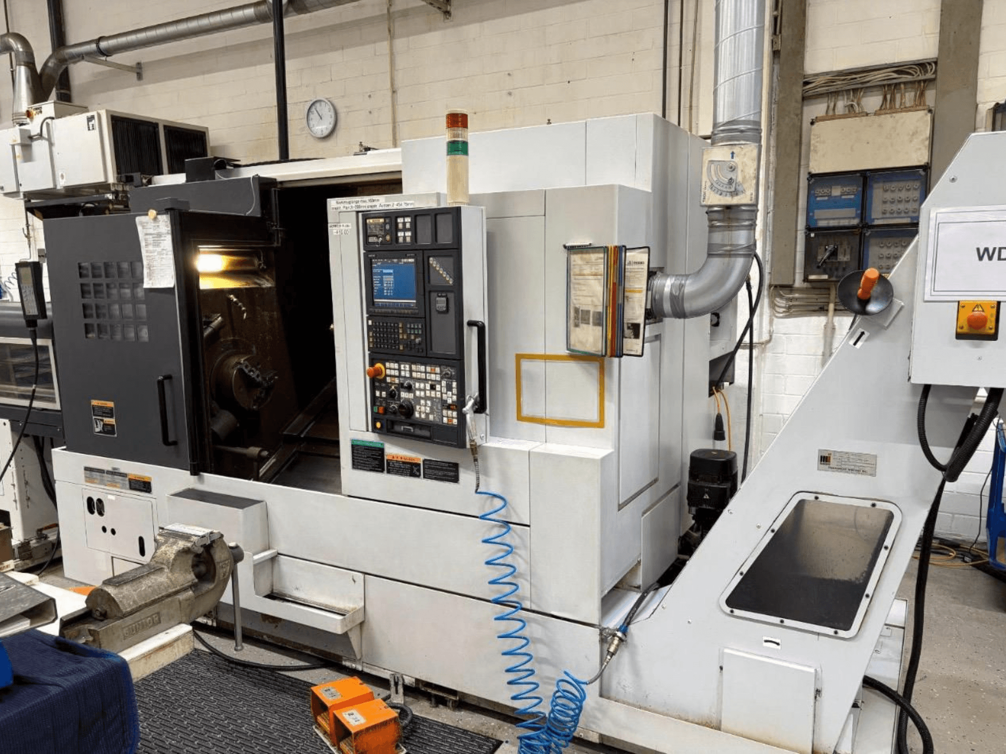 Centrum tokarsko-frezarskie MORI SEIKI NL 2500 SY, widok z przodu, pokazujący panel sterowania i obszar obróbki. Widoczny układ chłodzenia i akcesoria.