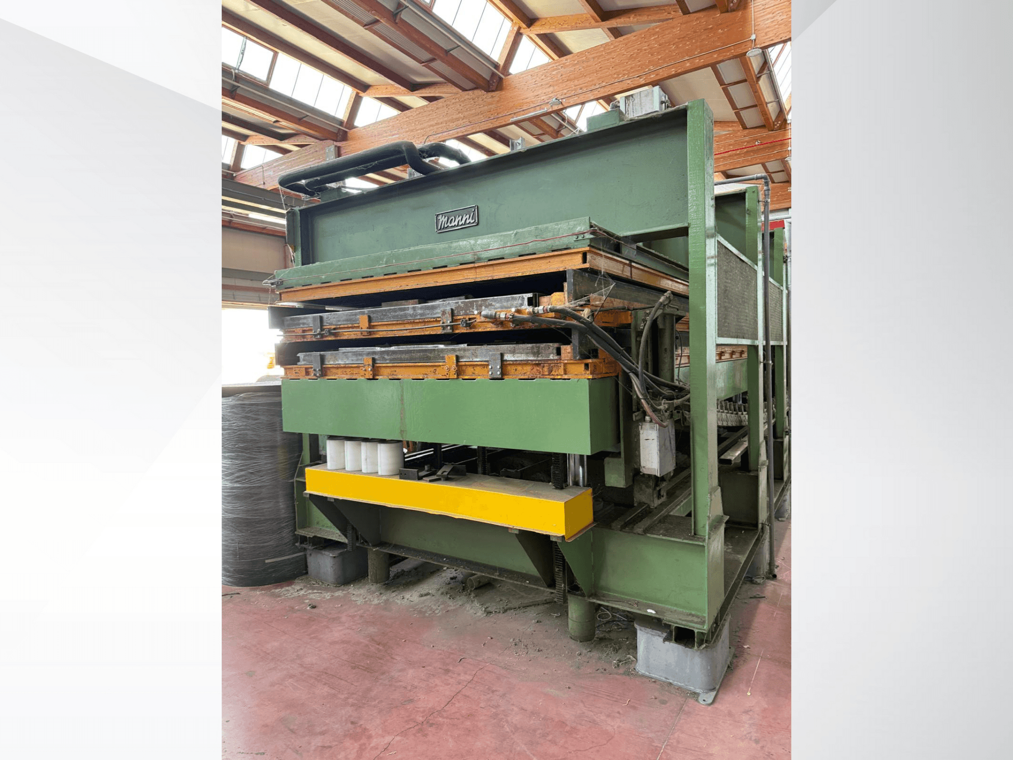 Prasa hydrauliczna Manni, widok z boku, z zielonym metalowym korpusem, żółtą podstawą i wieloma widocznymi przewodami hydraulicznymi.