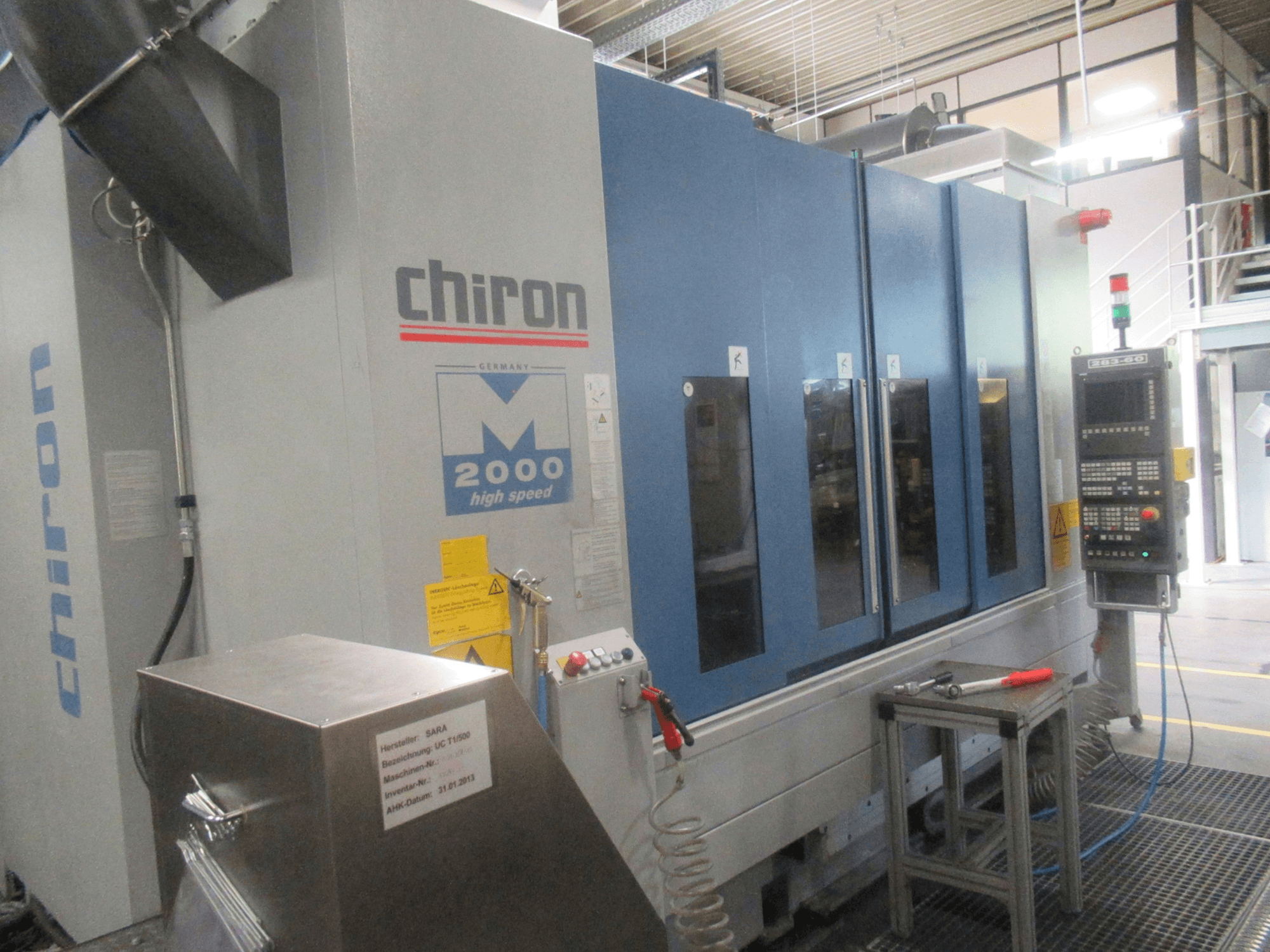 Pionowe centrum obróbcze CHIRON Mill 2000 – widok z przodu z panelem sterowania, w niebieskiej kolorystyce, z widocznymi elementami umożliwiającymi pracę z dużą prędkością.