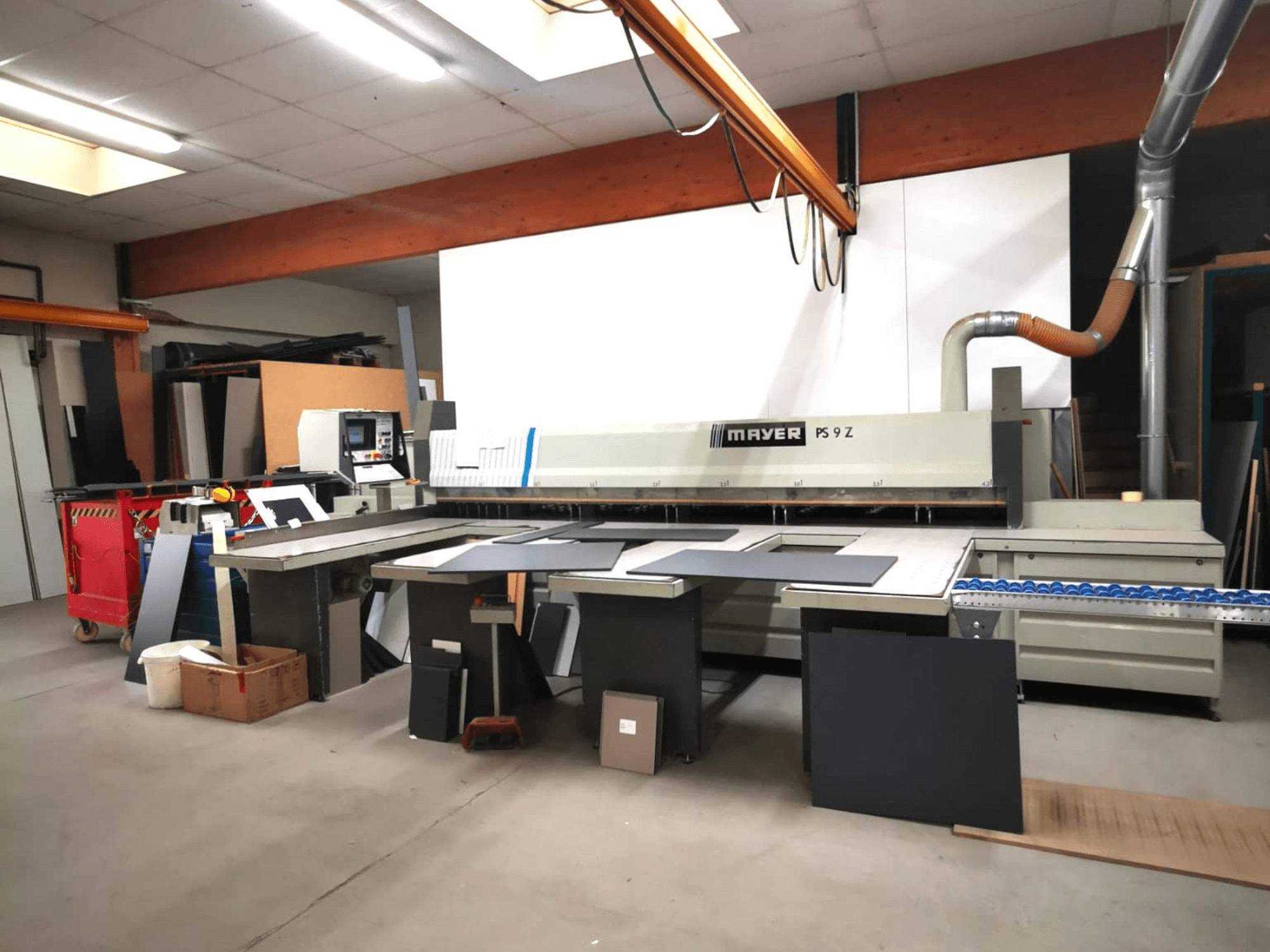 Maszyna do cięcia MAYER PS9 Z w warsztacie, widok z przodu, widoczne różne materiały i system przenośników.