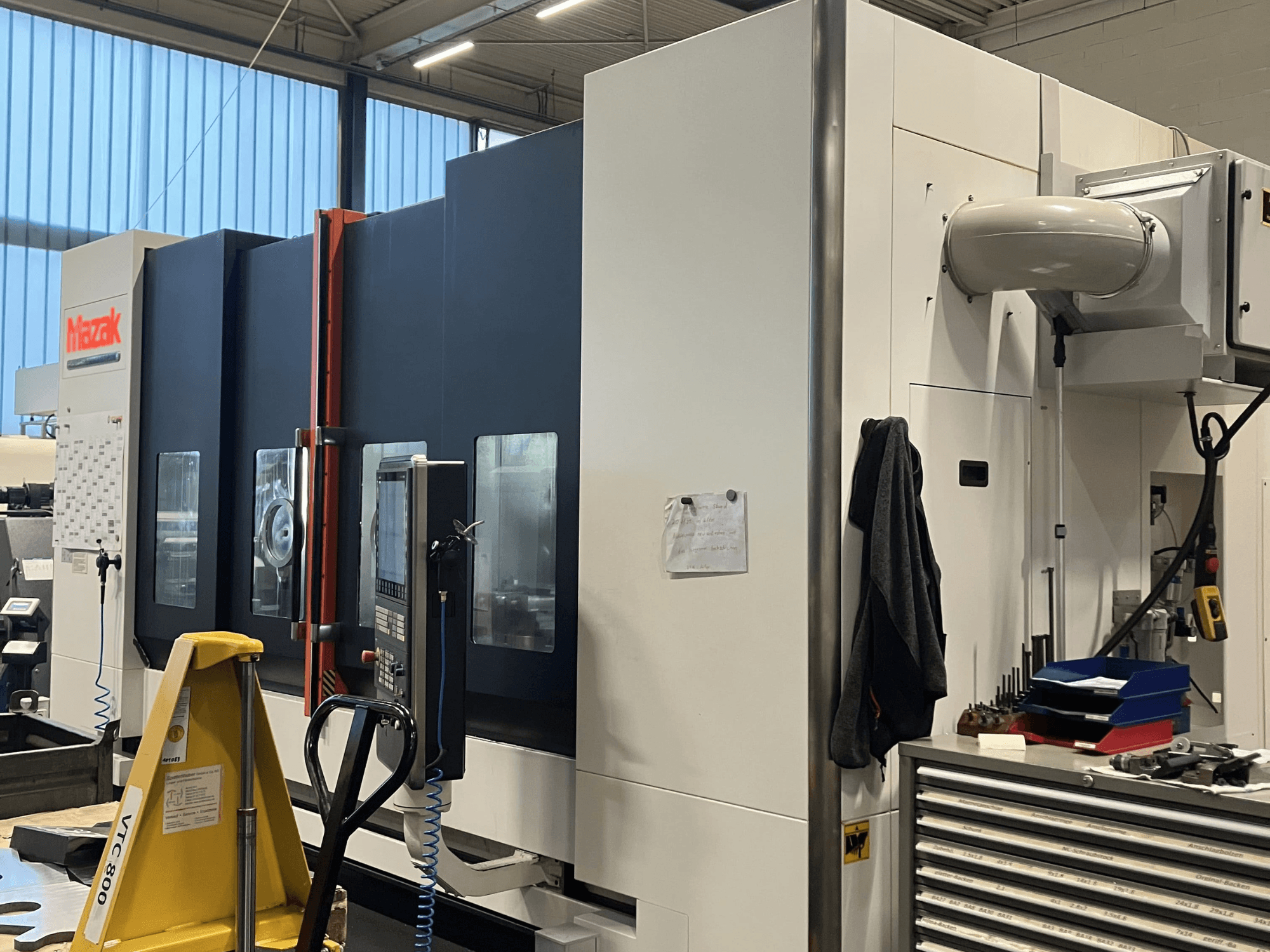 Maszyna CNC Mazak widziana z boku, prezentująca panel sterowania i funkcje bezpieczeństwa w warunkach warsztatowych.