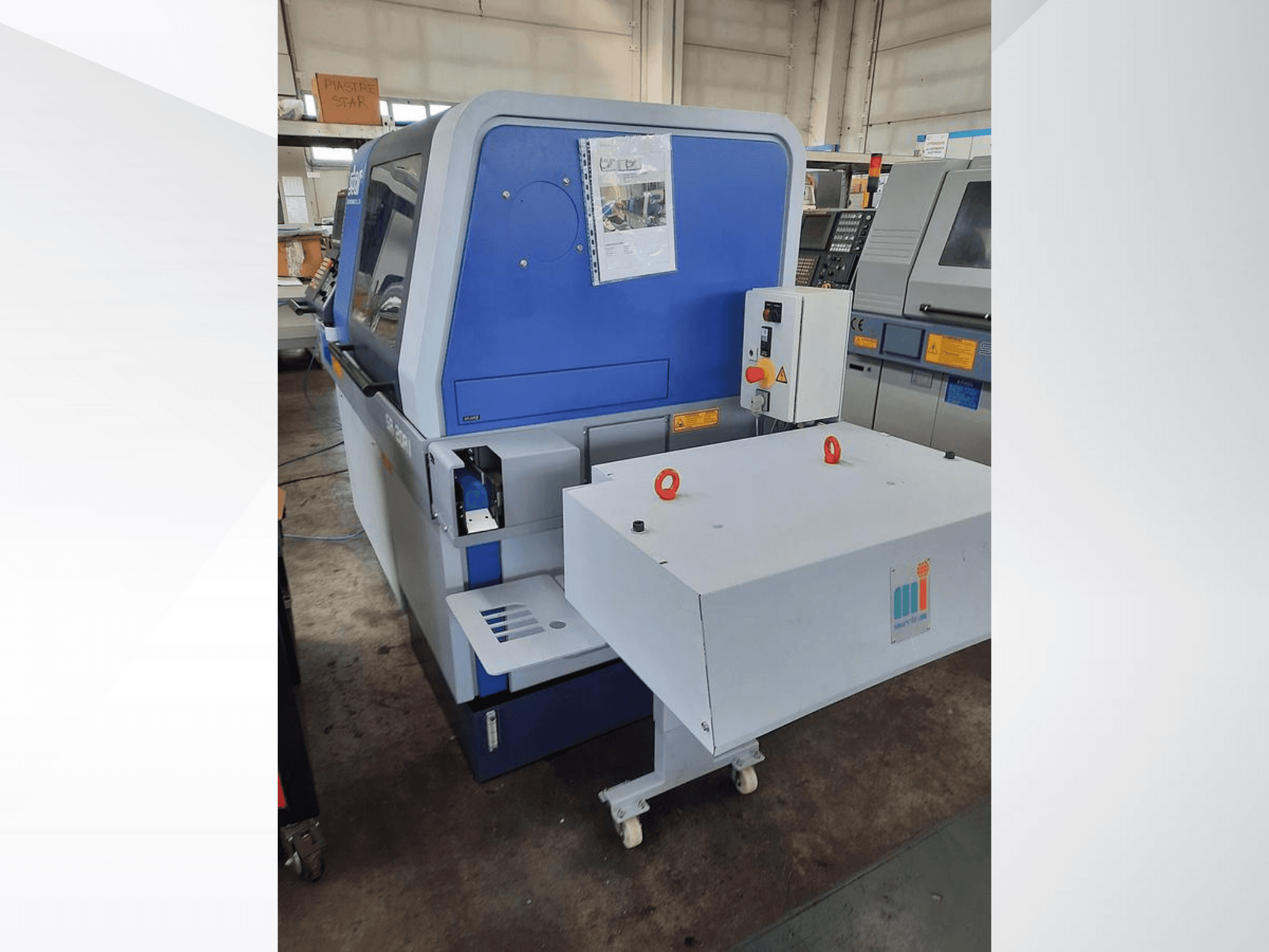 Niebieska maszyna przemysłowa z białym przenośnikiem, pokazująca panel sterowania i dołączone zabezpieczenia, widok z boku.