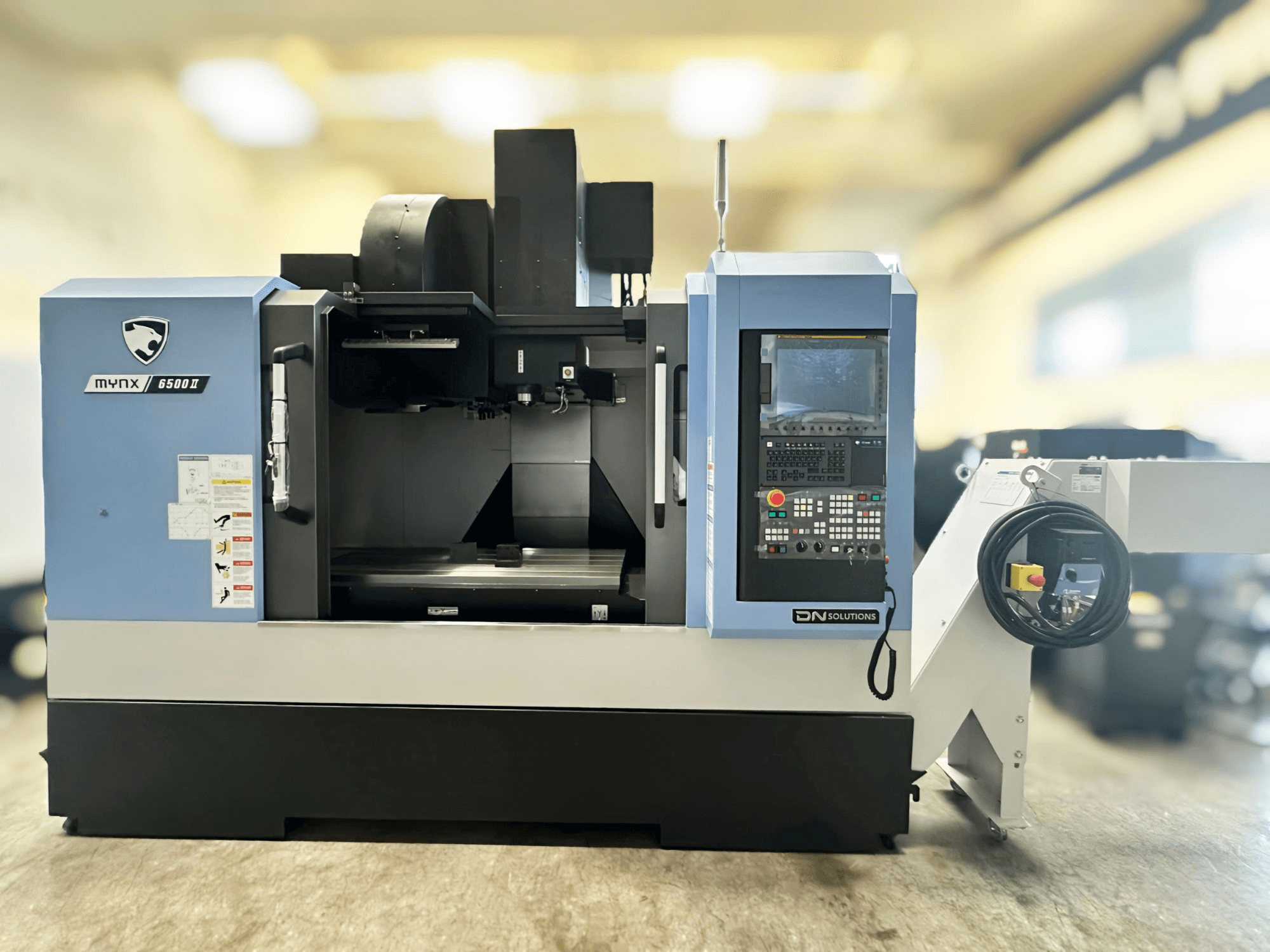 Pionowe centrum obróbcze DN SOLUTIONS MYNX 6500 II – widok z przodu, z panelem sterowania i interfejsem operacyjnym.