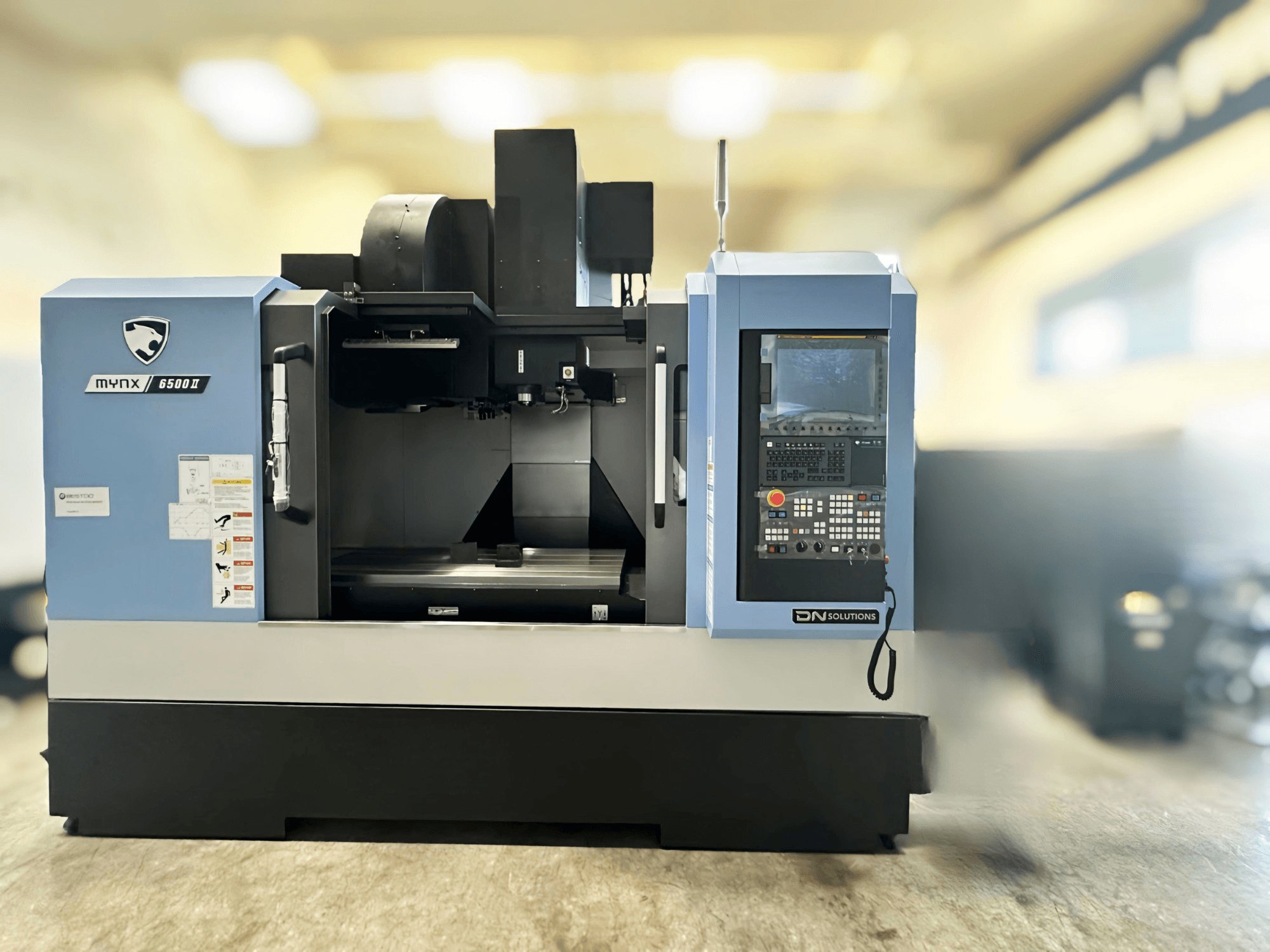 Pionowe centrum obróbcze DN SOLUTIONS MYNX 6500 II – widok z przodu przedstawiający panel sterowania i obszar roboczy.