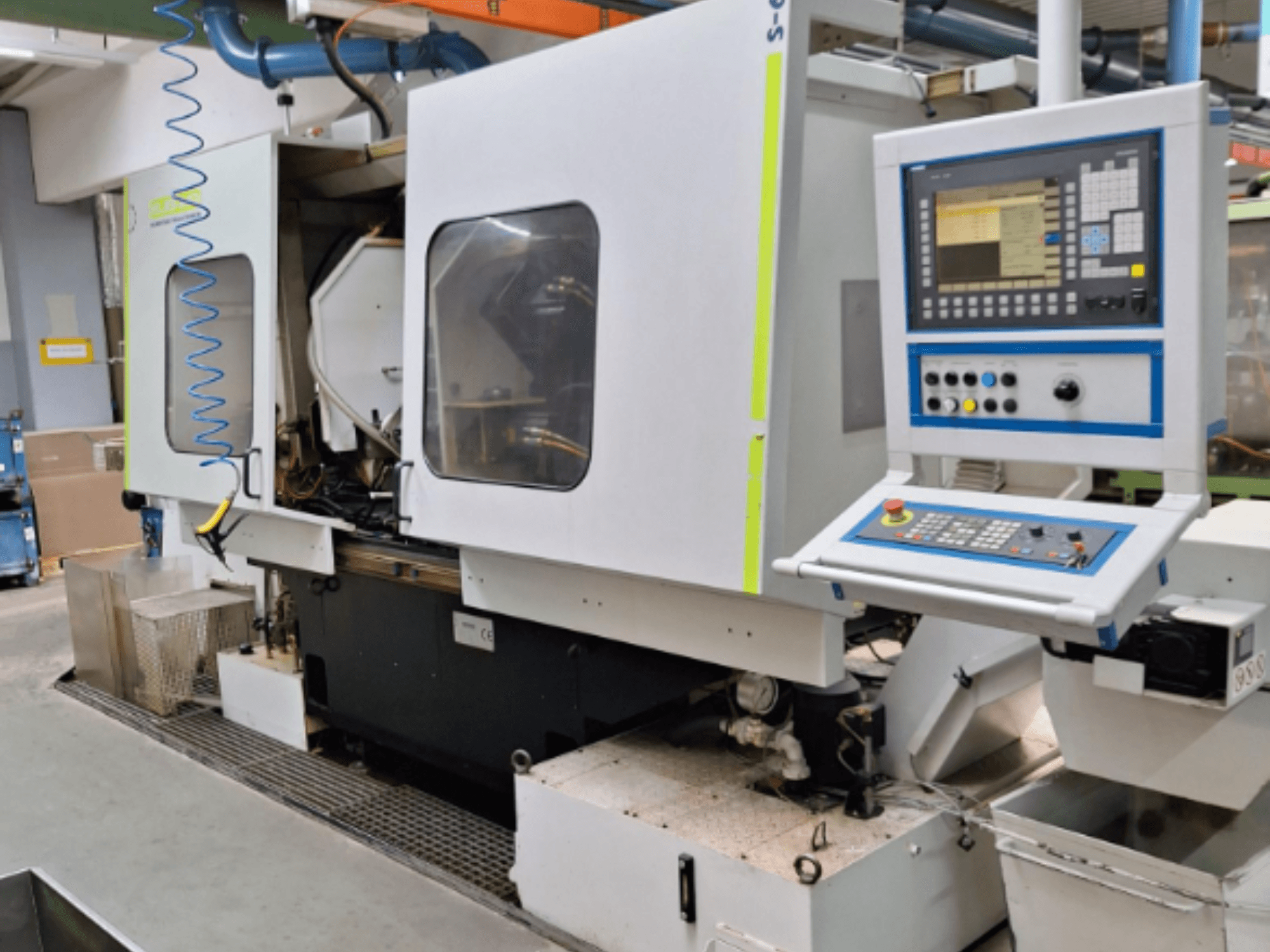 Frezarka przemysłowa z panelem sterowania, widok z boku, z podwójnymi komorami i widocznymi połączeniami rurowymi.