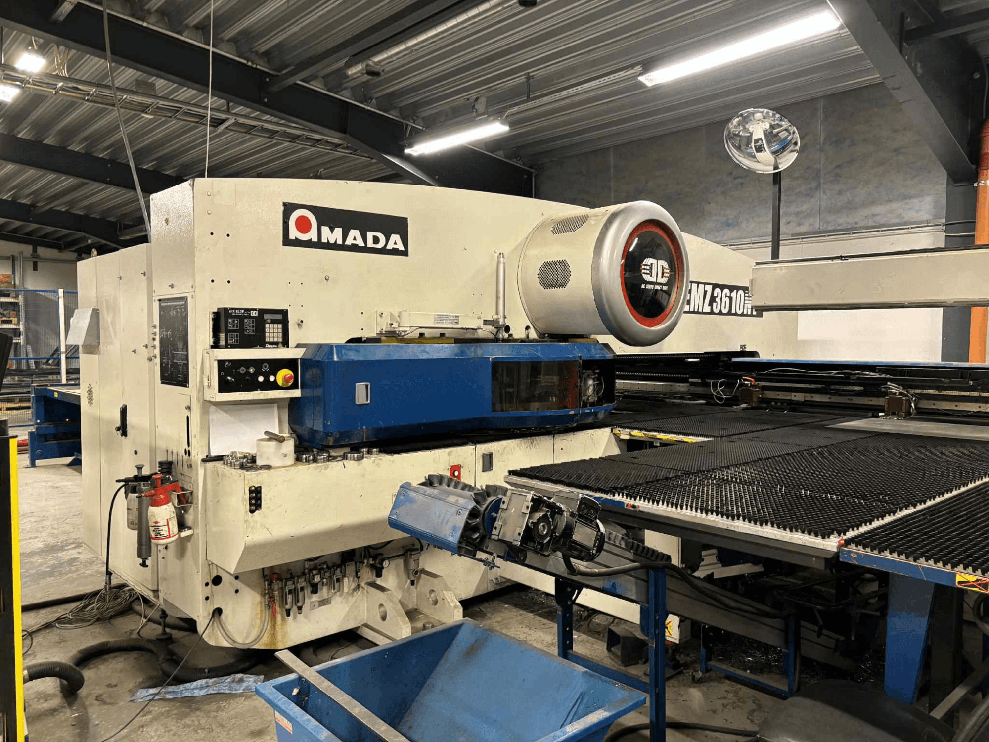 Prasa wykrawająca Amada EMZ3610H widziana od przodu; posiada elementy sterujące, niebieskie łoże i wyposażenie bezpieczeństwa.