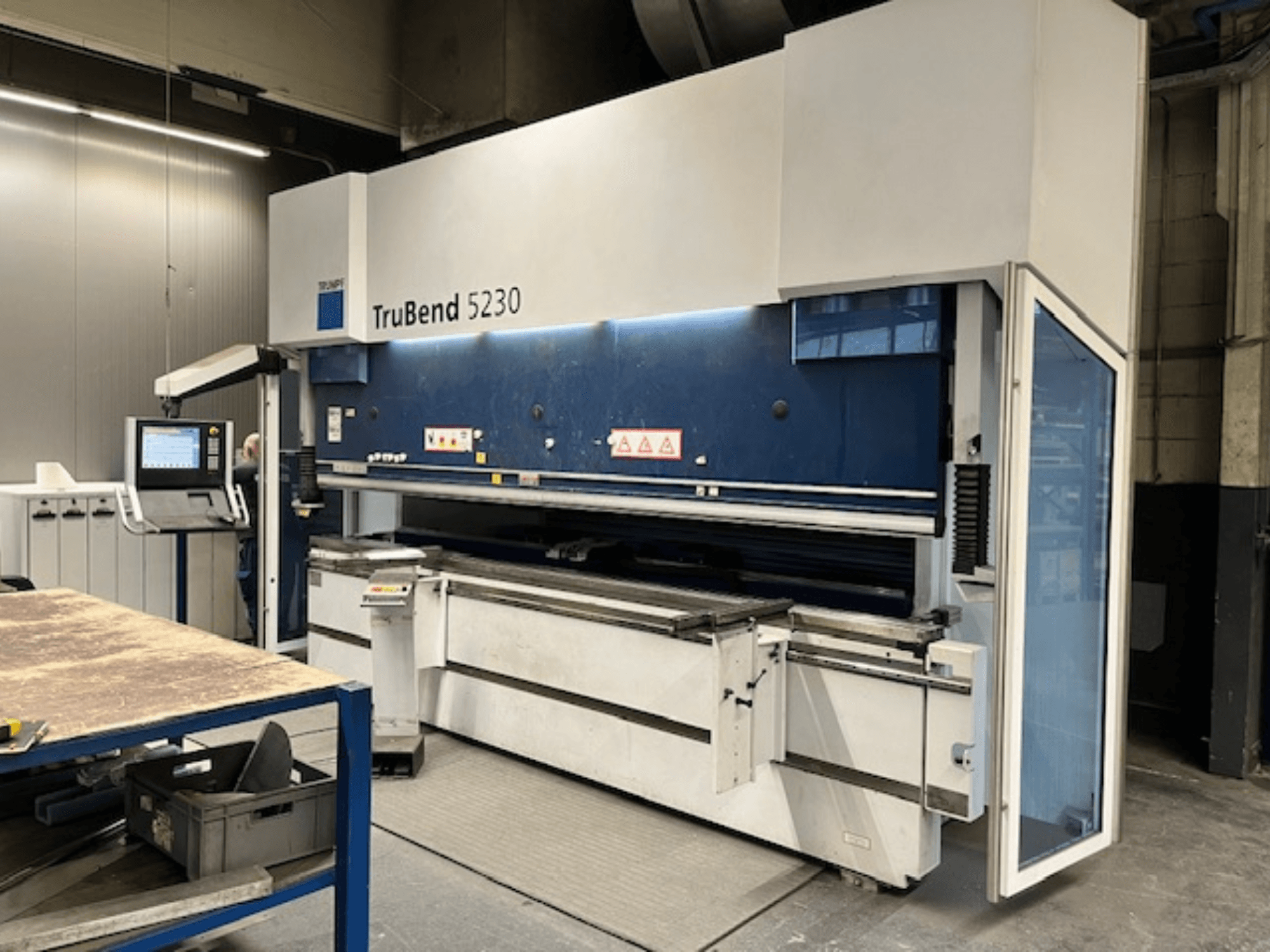 Giętarka TruBend 5230 w warunkach przemysłowych; widok z przodu pokazujący panel sterowania, zabezpieczenia i stół roboczy.