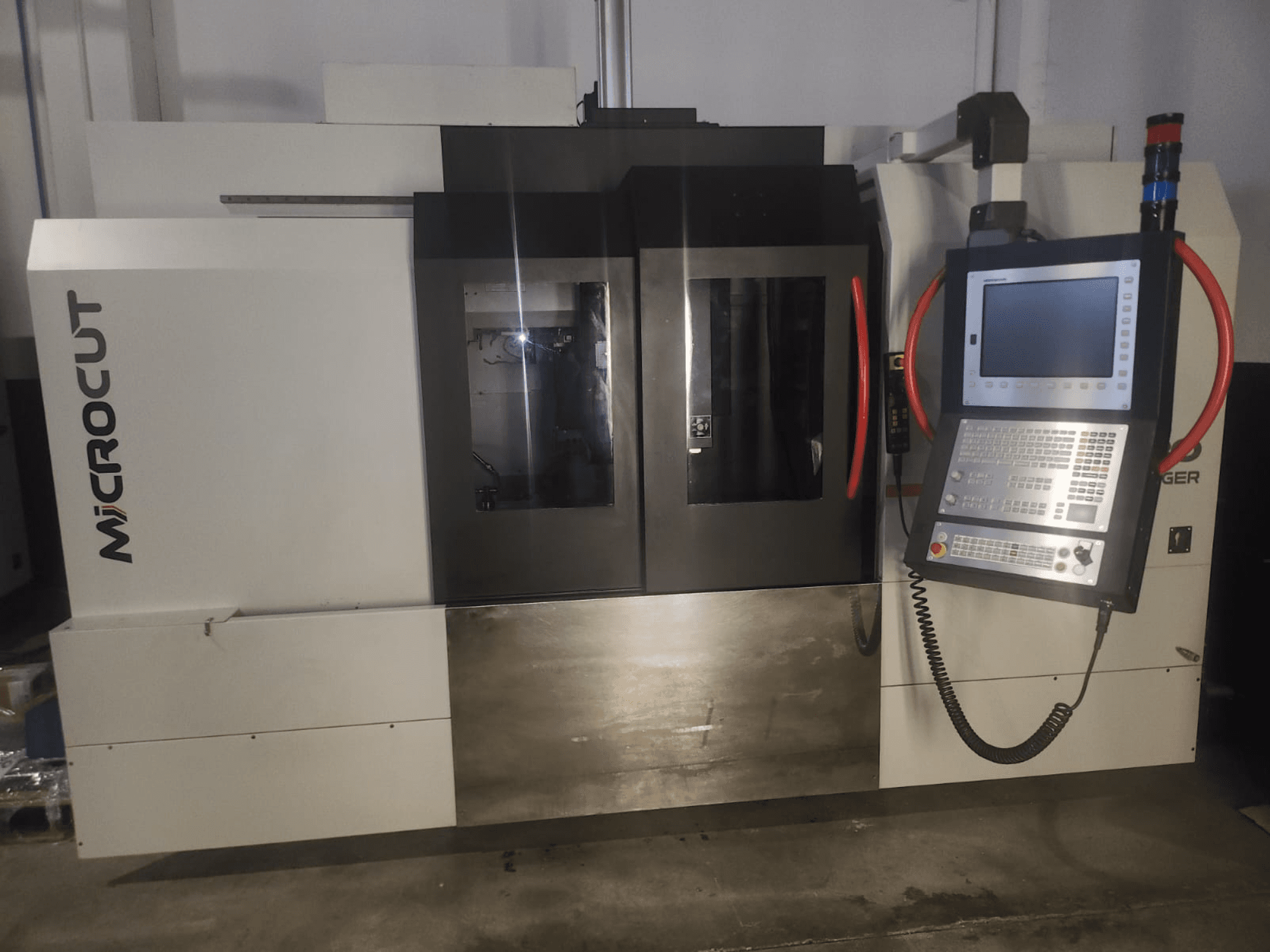 Maszyna CNC Microcut widziana od przodu; posiada panel sterowania, podwójne okna, przemysłową konstrukcję i metaliczne wykończenie.