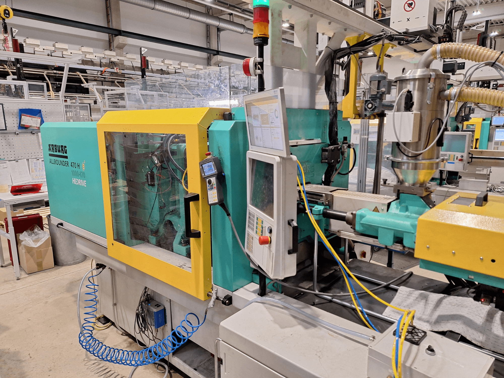 Hydrauliczna wtryskarka Arburg 470 H 1000-170, widok z boku z panelem sterowania i układem podawania.