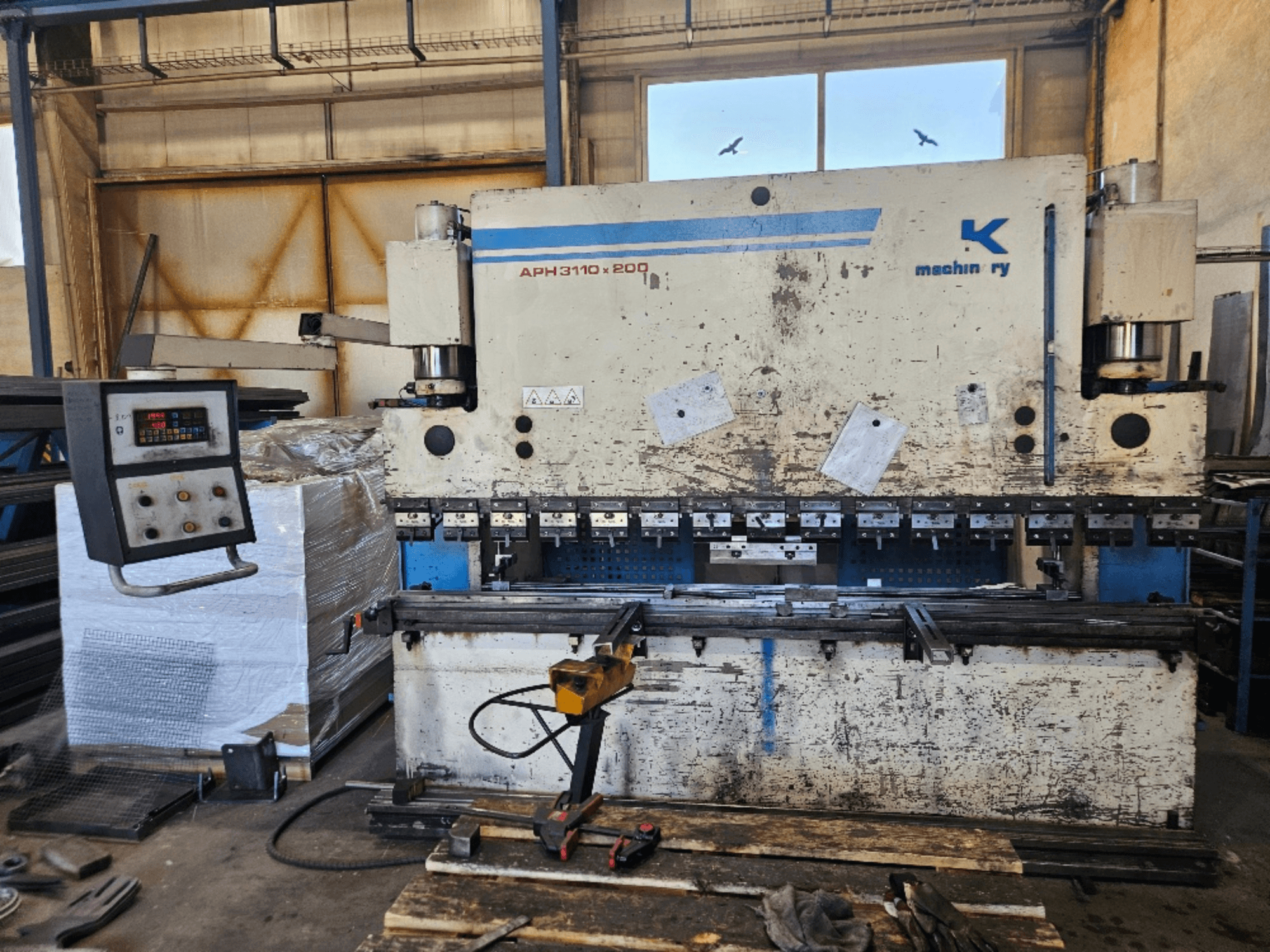 Prasa krawędziowa Baykal APH 3110x200 w warsztacie, widok z przodu, widoczny panel sterowania, blachy i narzędzia.