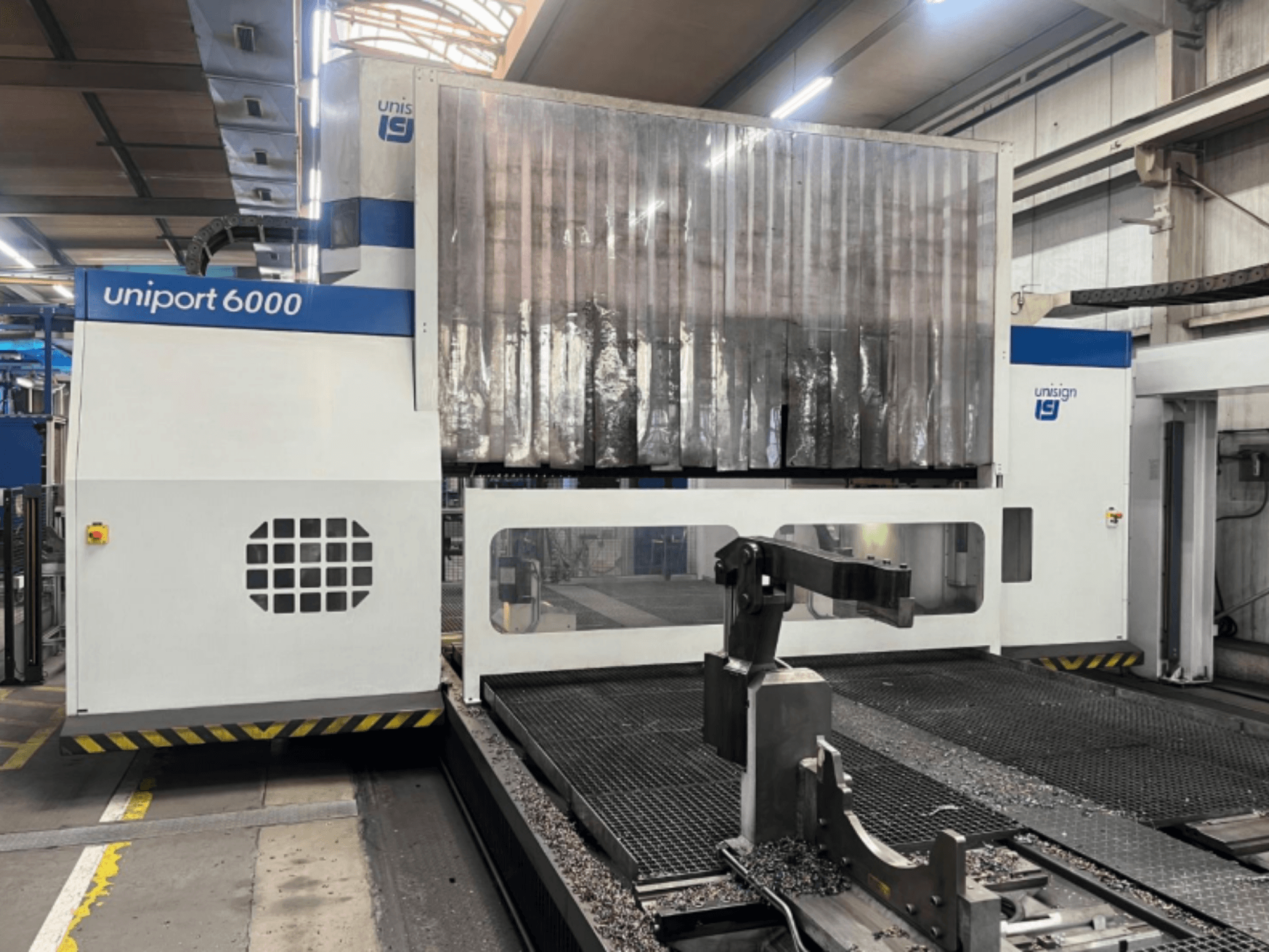 Frezarka bramowa Unisign uniport 6000, widok z przodu, przedstawiający strukturę maszyny i obszar cięcia z wiórami metalowymi.