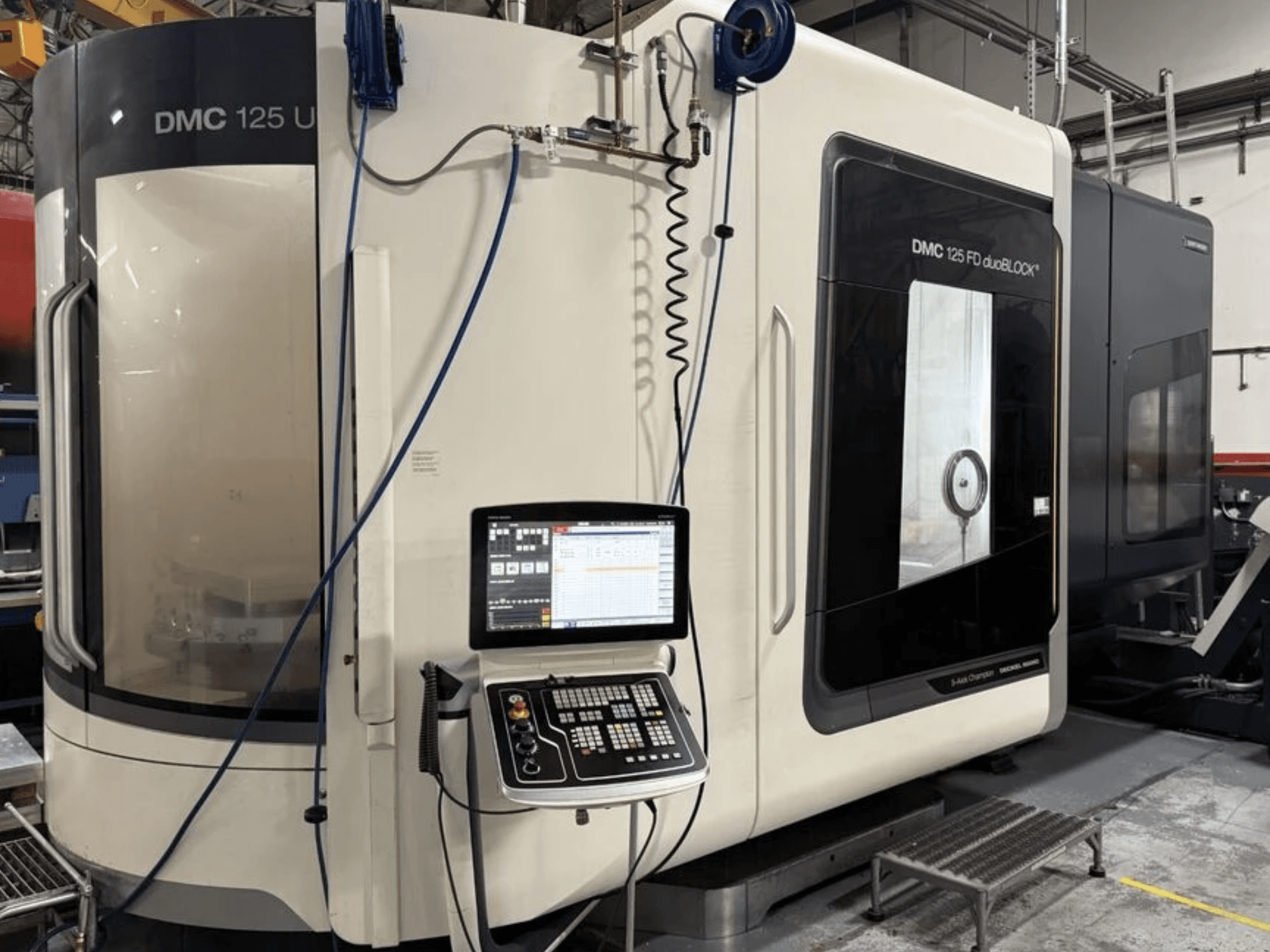 Uniwersalne centrum obróbcze DMG MORI DMC 125 U duoBLOCK, widok z przodu z panelem sterowania i powierzchniami odbijającymi światło.