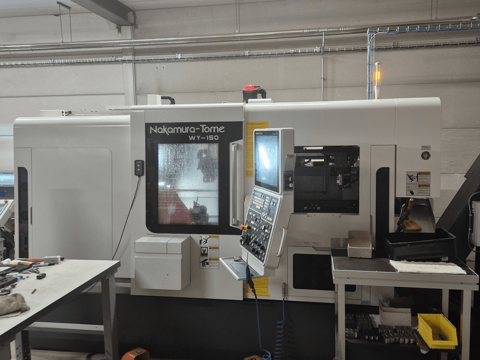 Tokarka CNC Nakamura-Tome WY-150 w widoku z boku, z panelem sterowania, przezroczystym oknem i widocznym obszarem roboczym.