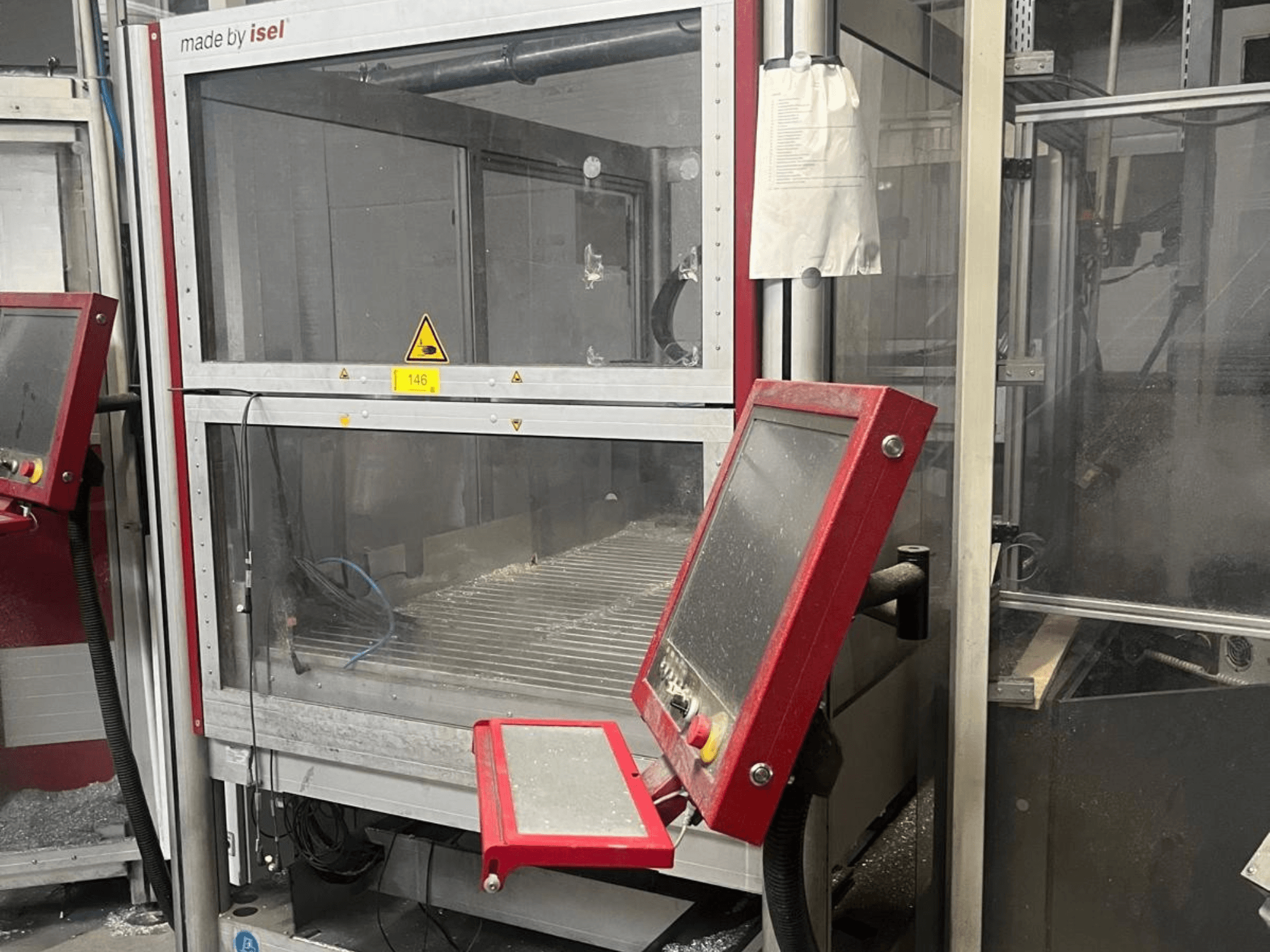 Pionowe centrum obróbcze ISEL FLATCOM M 30 – widok z przodu przedstawiający panel sterowania, obszar roboczy oraz elementy zabezpieczające.