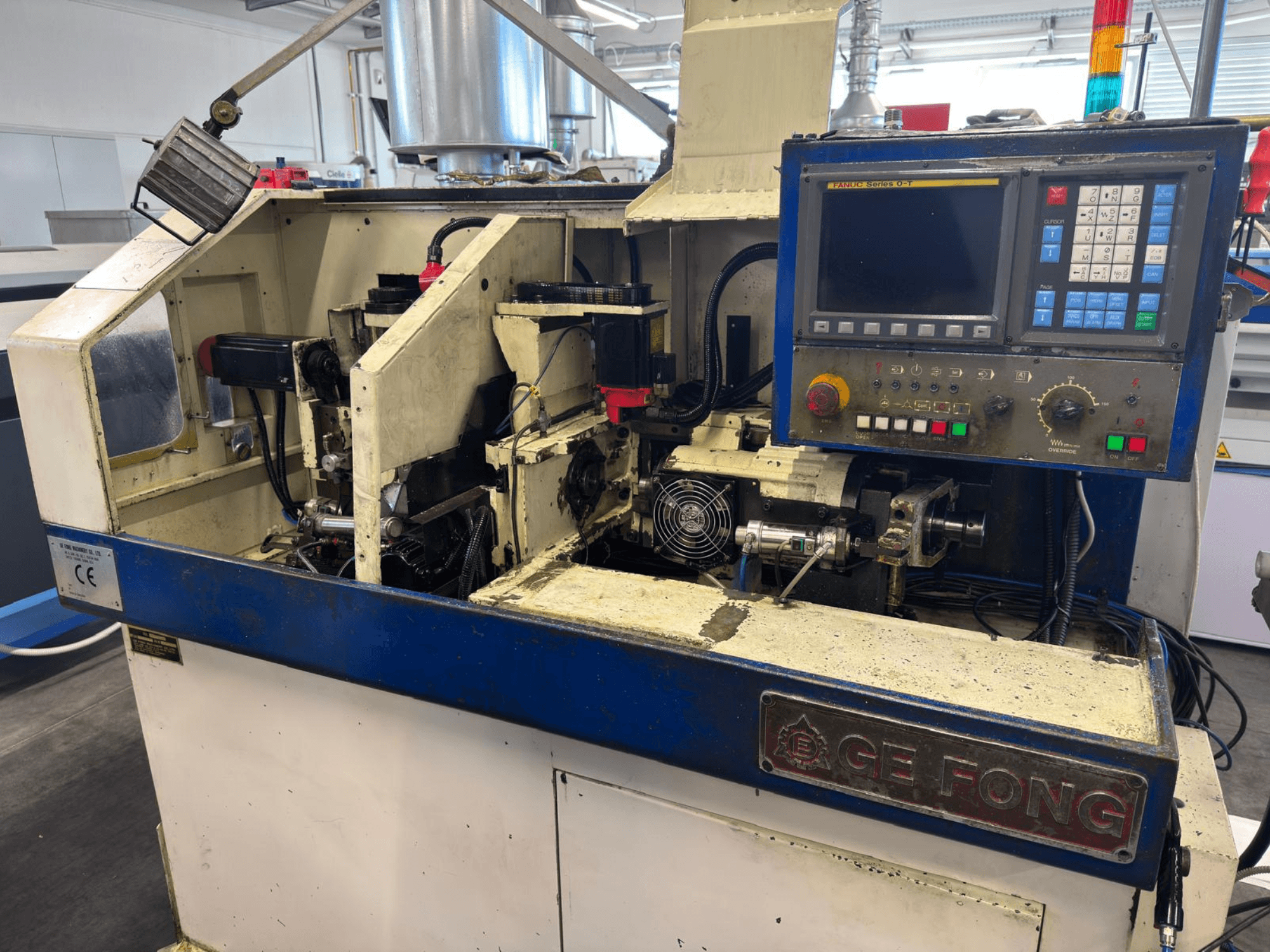 Maszyna przemysłowa GE FONG w widoku z przodu, pokazująca elementy wewnętrzne, panel sterowania i części operacyjne.