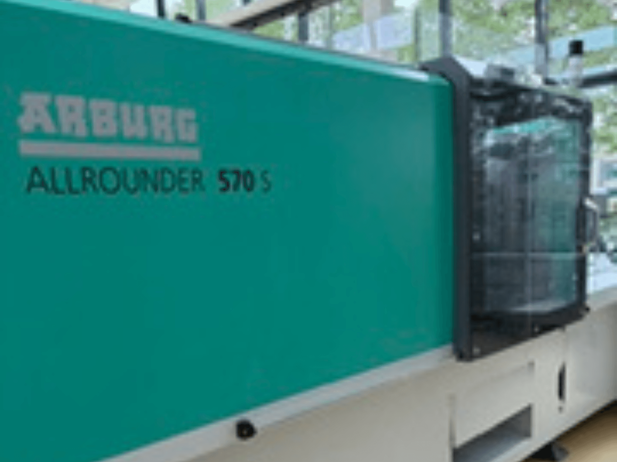 Widok z przodu wtryskarki Arburg ALLROUNDER 570 S 1600-290 z turkusową obudową i jednostką wtryskową, przedstawiający część konstrukcji wtryskarki.
