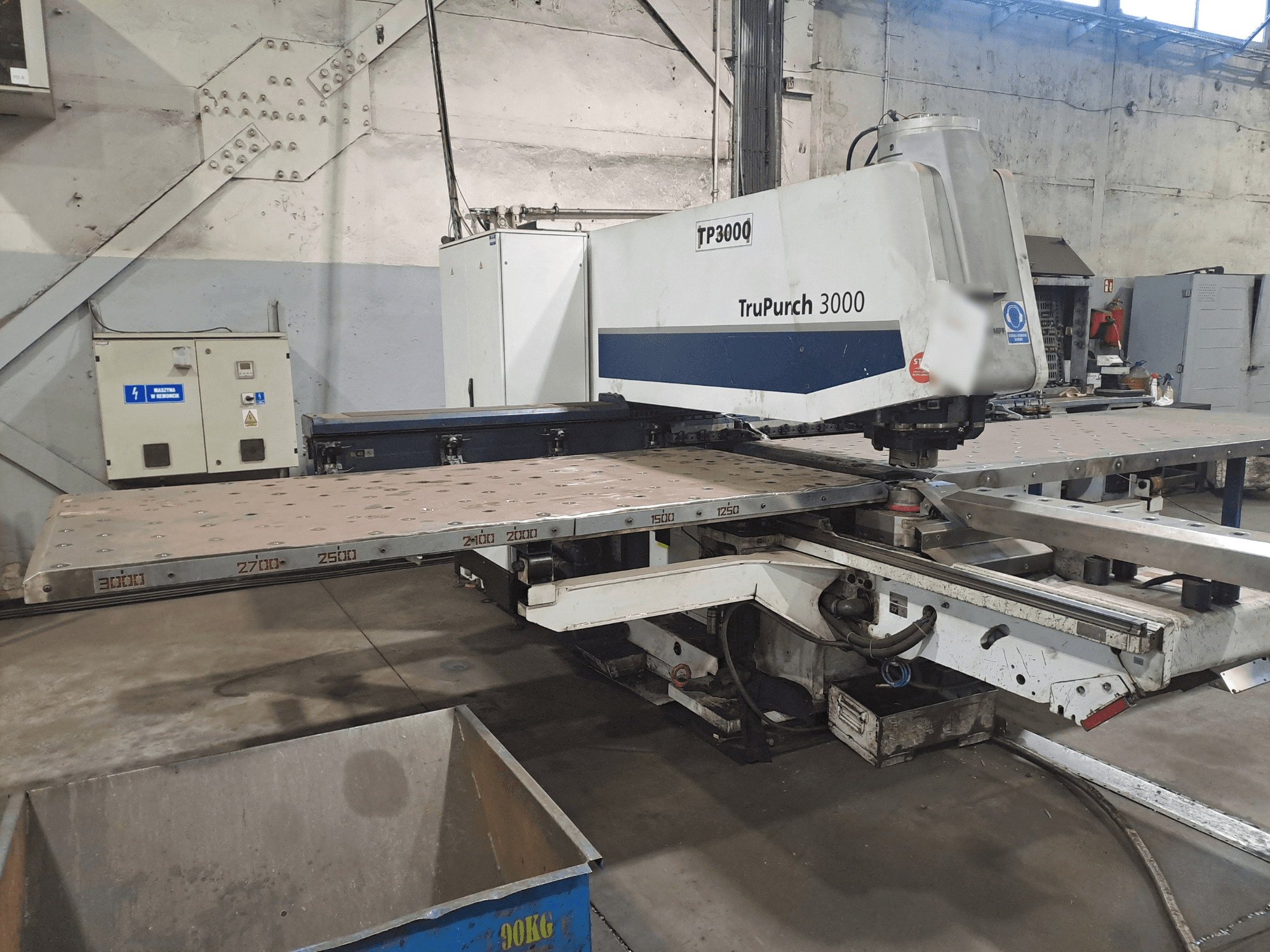 Maszyna CNC TruPunch 3000 pokazana od przodu, z dużą metalową płytą i oznaczeniami pomiarowymi, w warunkach przemysłowych.