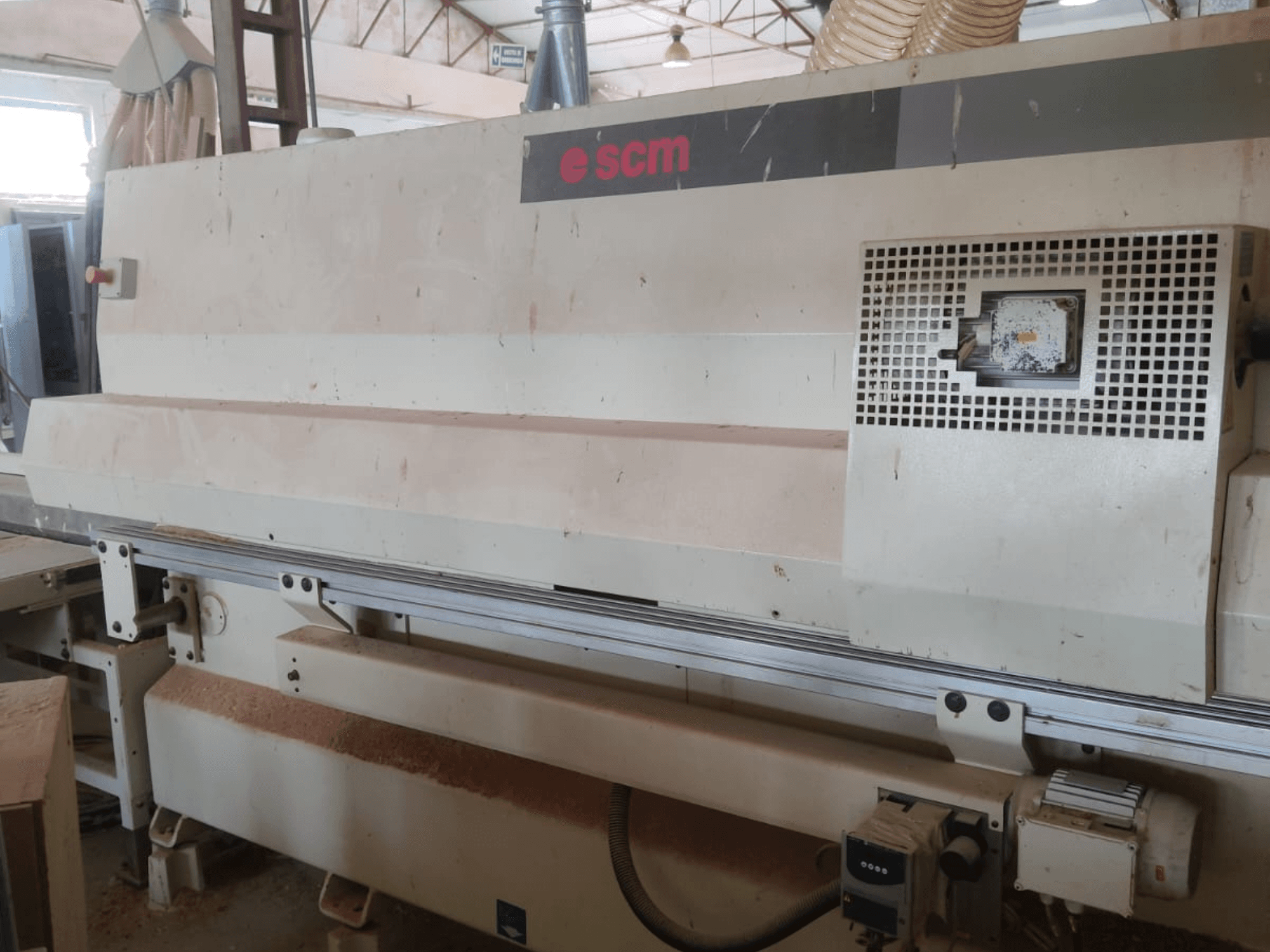 Centrum obróbki drewna CNC SCM Windor60, widok z przodu. Widoczne są elementy sterujące maszyny oraz system odpylania, a pod spodem wióry drzewne.