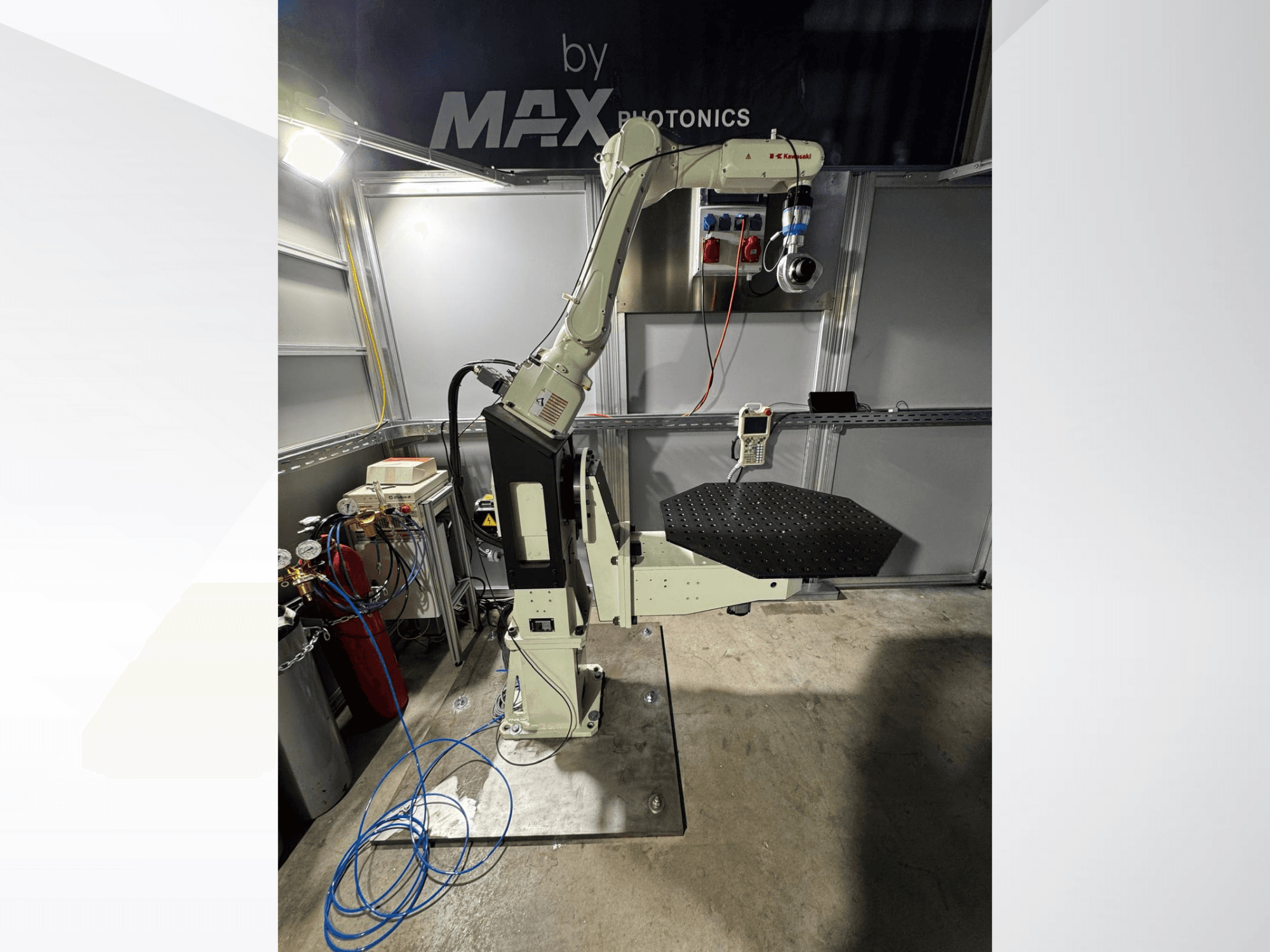 Urządzenie z ramieniem robotycznym Max Photonics, widok z przodu, z czarną perforowaną platformą i panelem sterowania ze wskaźnikami i kablami.