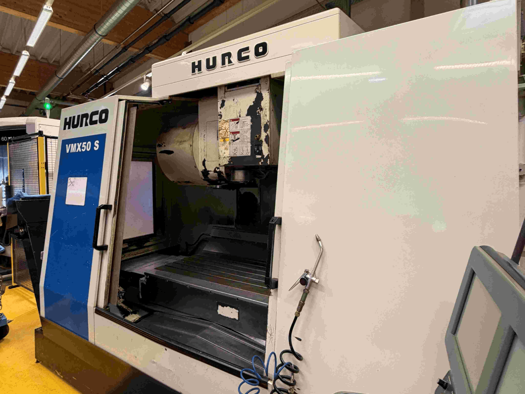 Pionowe centrum obróbcze Hurco VMX50 S, widok z boku, otwarte drzwi i panel sterowania.