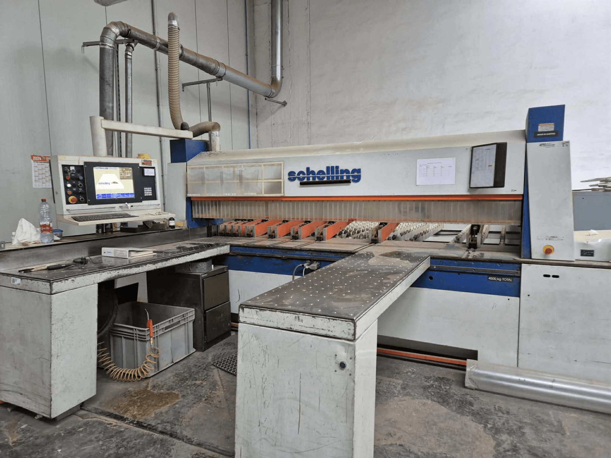 Maszyna do cięcia Schaublin w widoku z boku, wyposażona w interfejs komputerowy, ostre ostrza i solidną metalową powierzchnię roboczą.