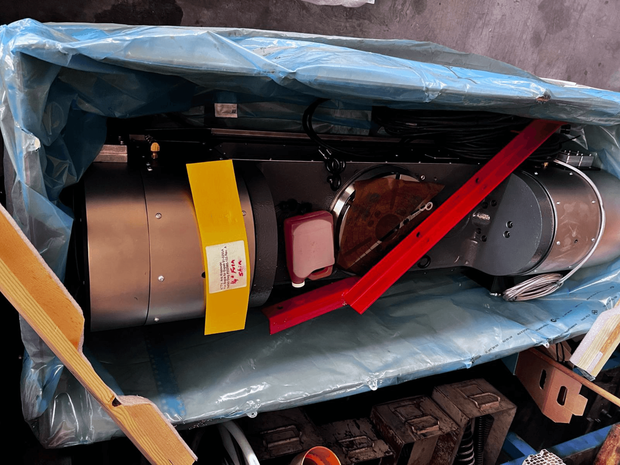 Urządzenie silnikowe częściowo widoczne w opakowaniu, posiada srebrną obudowę, kolorowe wskaźniki i czerwony wspornik.