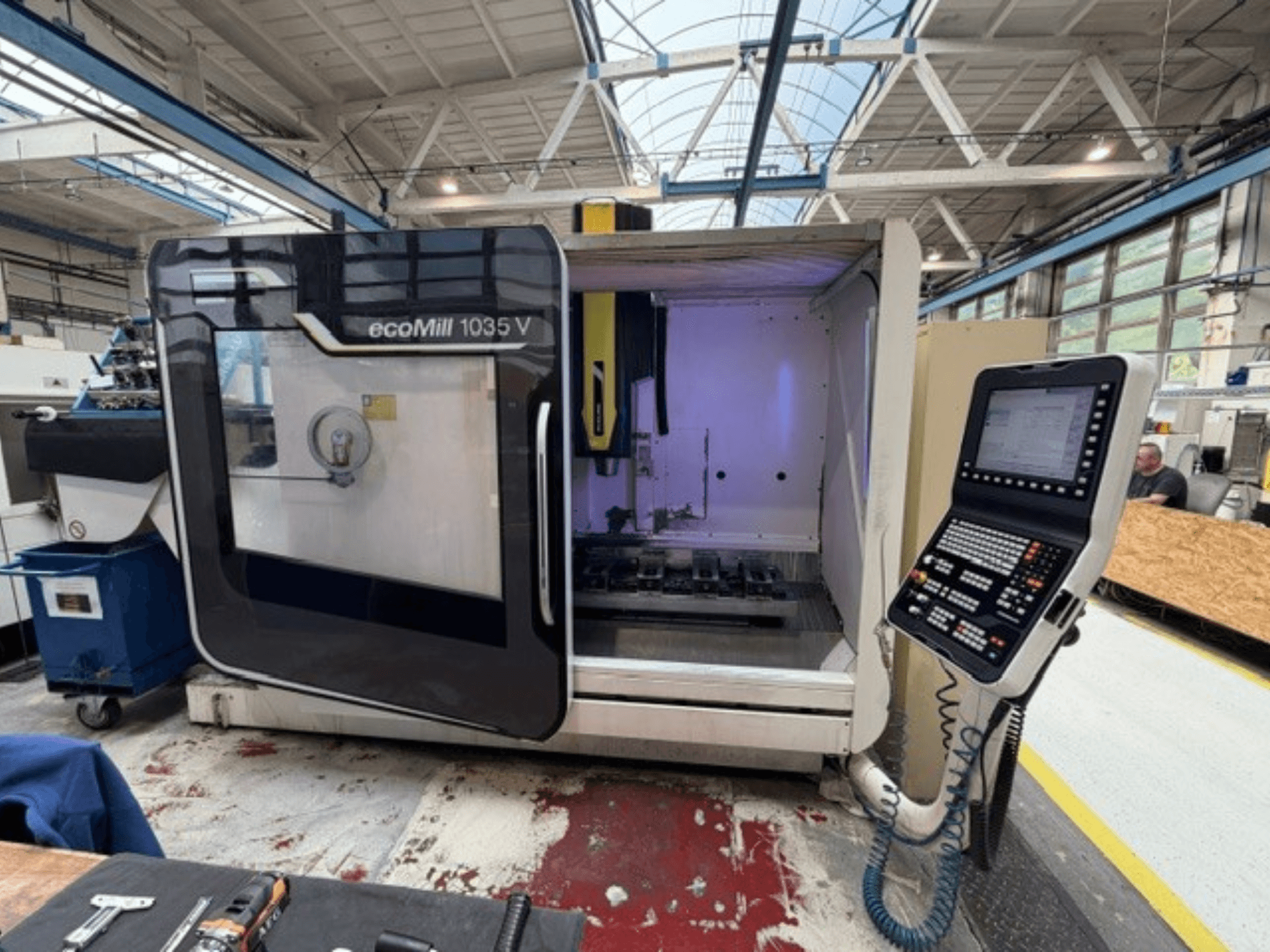 Widok z przodu pionowego centrum obróbczego DMG MORI ecoMill 1035V z otwartymi drzwiami, ukazujący panel sterowania i obszar roboczy wewnątrz urządzenia.