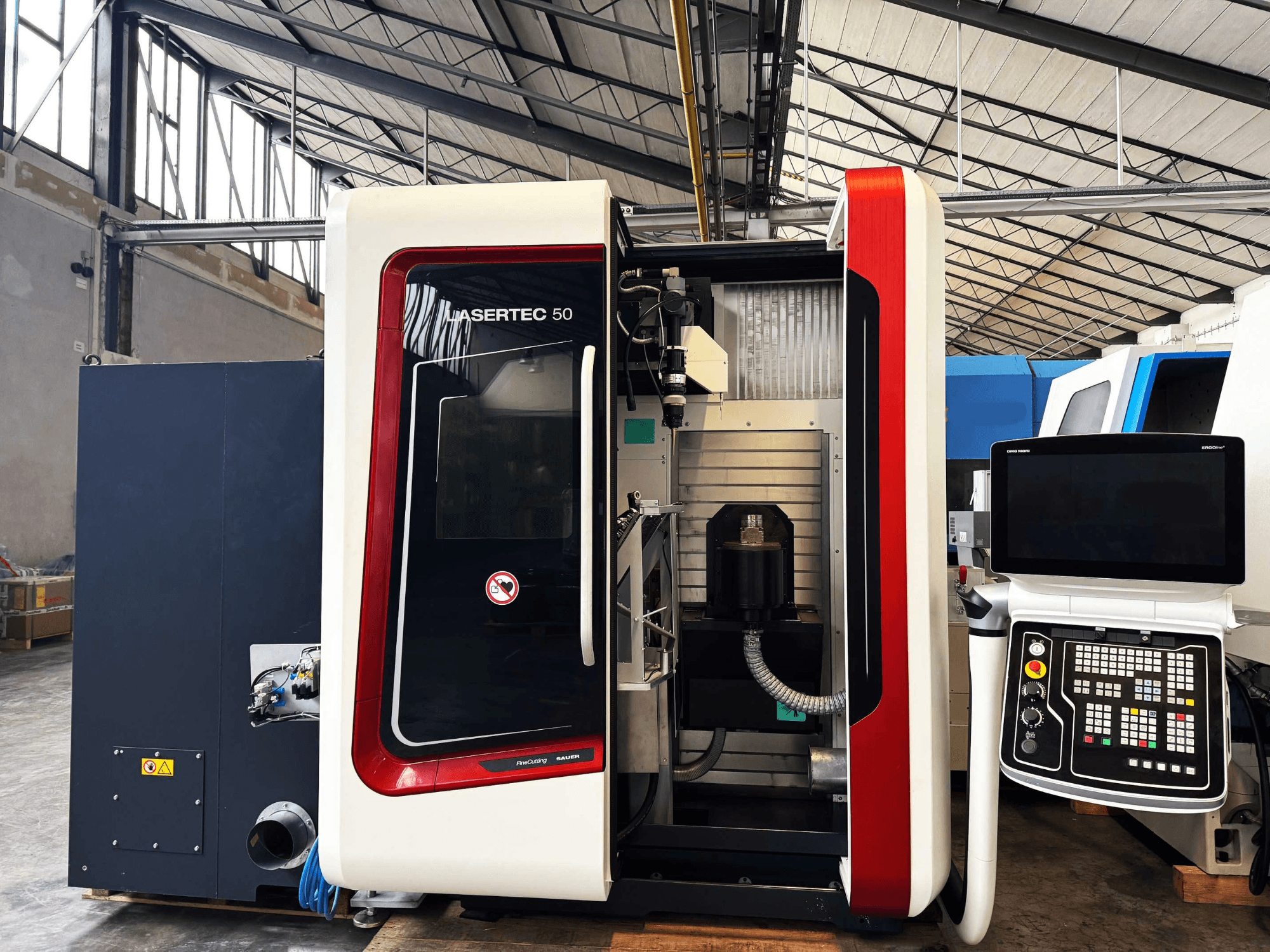 Maszyna CNC LaserTec 50 w widoku z boku, z czarno-białym panelem sterowania, widocznym uchwytem narzędziowym i ustawieniem przemysłowym.